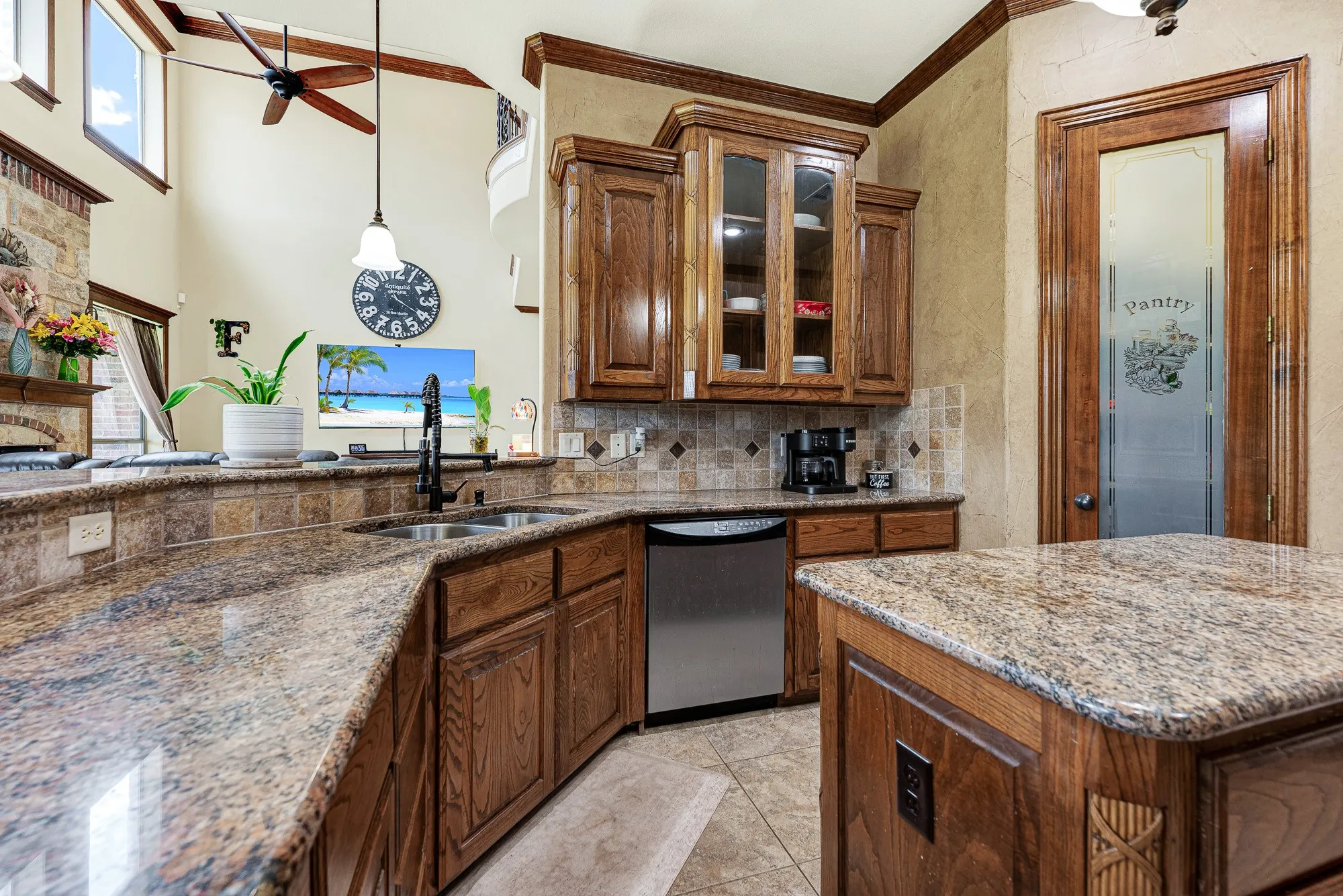 Glass-front upper cabinets reflect the ambient light, while the open boundary seamlessly links the workspace to the soaring living area. You can effortlessly pass appetizers across the counter while staying fully connected to the conversation next door.