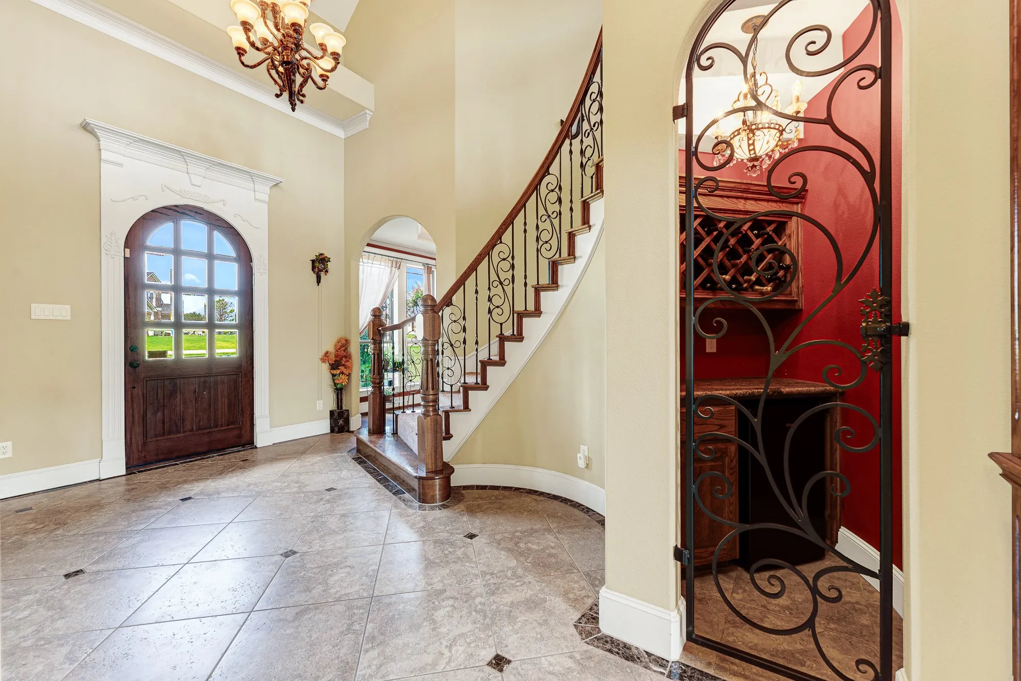 An elegant, arched front door pairs beautifully with a dedicated wine alcove secured by custom, swirling iron craftsmanship. It is the perfect setting to warmly greet your dinner guests with an exceptional vintage poured straight from your private collection