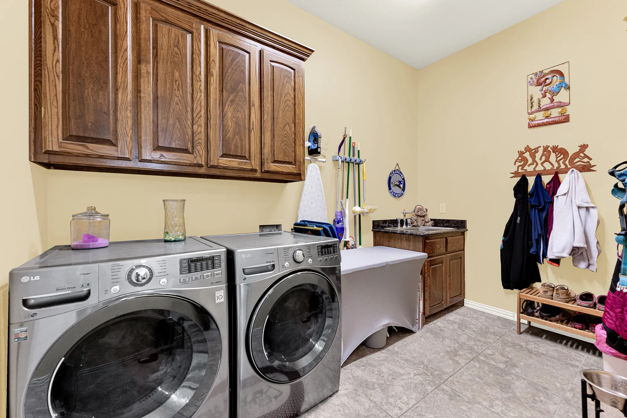 Richly stained overhead cabinets optimize the vertical wall space above efficient side-by-side appliances and a built-in utility sink. It makes tackling the weekly chores feel remarkably streamlined, keeping the rest of your home organized and entirely clutter-free.