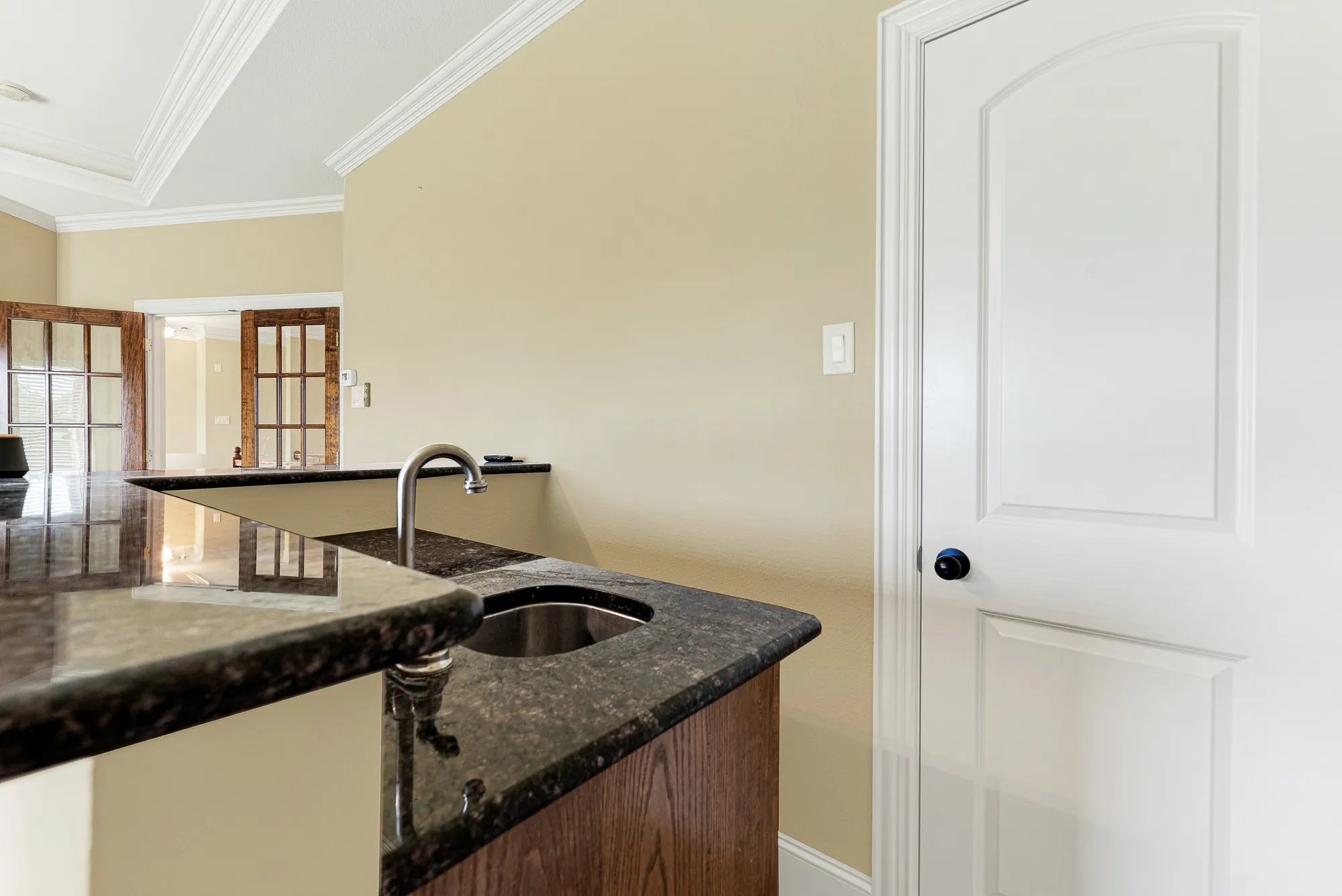 A sleek, dark granite countertop wraps around a convenient under-mount prep sink, creating a highly functional beverage hub. It is the perfect spot to mix a refreshing drink or set out snacks before settling in for an evening movie marathon.