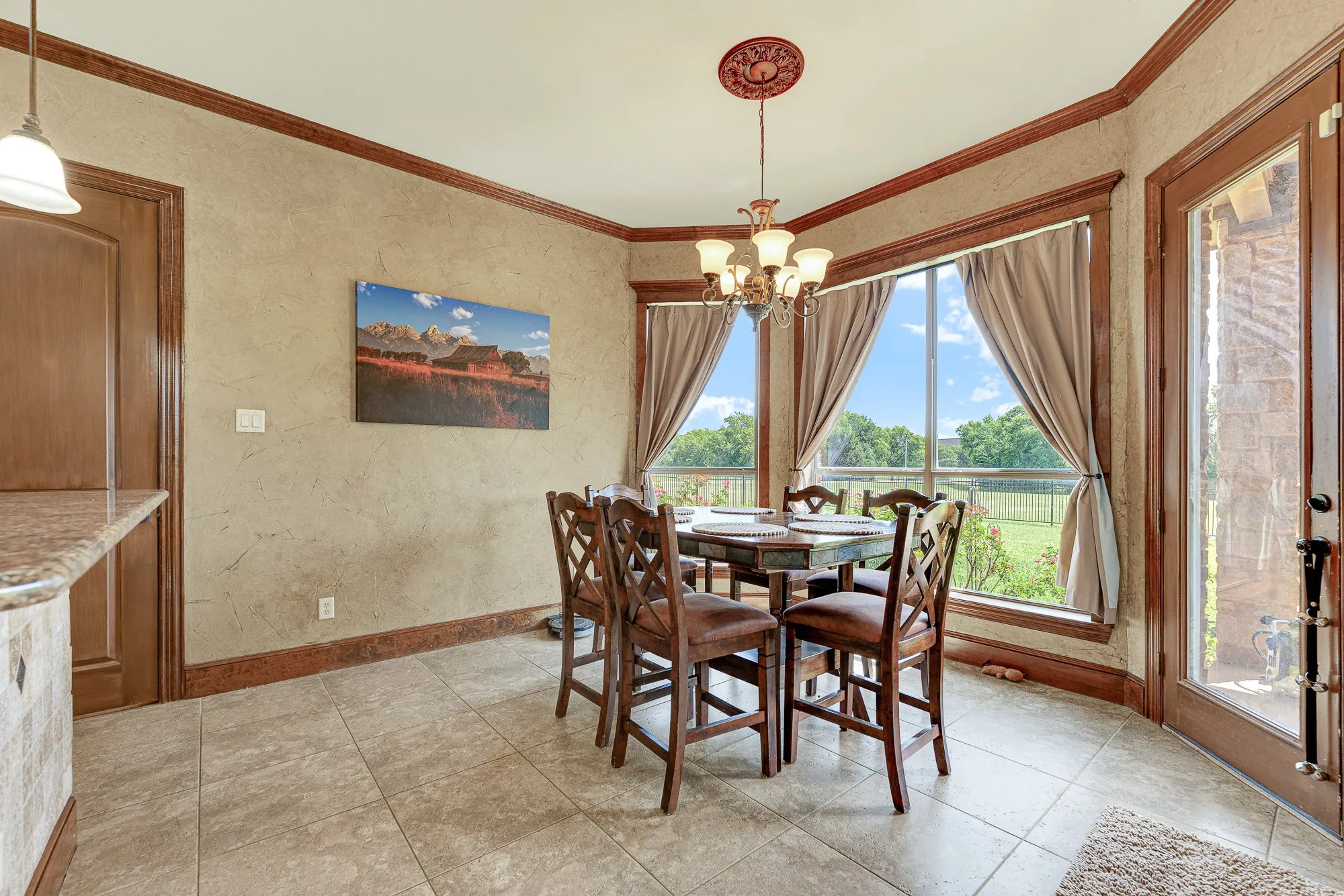 A wide bay of windows and a glass door draw the eye outward, filling the casual eating space with soft light. Savor a slow morning coffee right here, watching the sun move across your expansive green acreage.