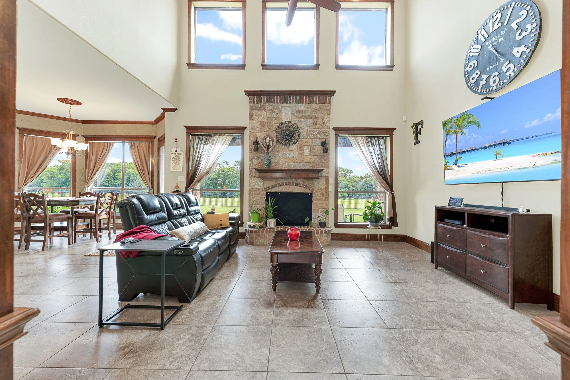 A towering, floor-to-ceiling stone fireplace serves as a grounding anchor between two tiers of stacked windows that look out to the expansive grounds. It's the ultimate spot to curl up with a favorite book on a lazy Sunday afternoon, bathed in an abundance of natural light.