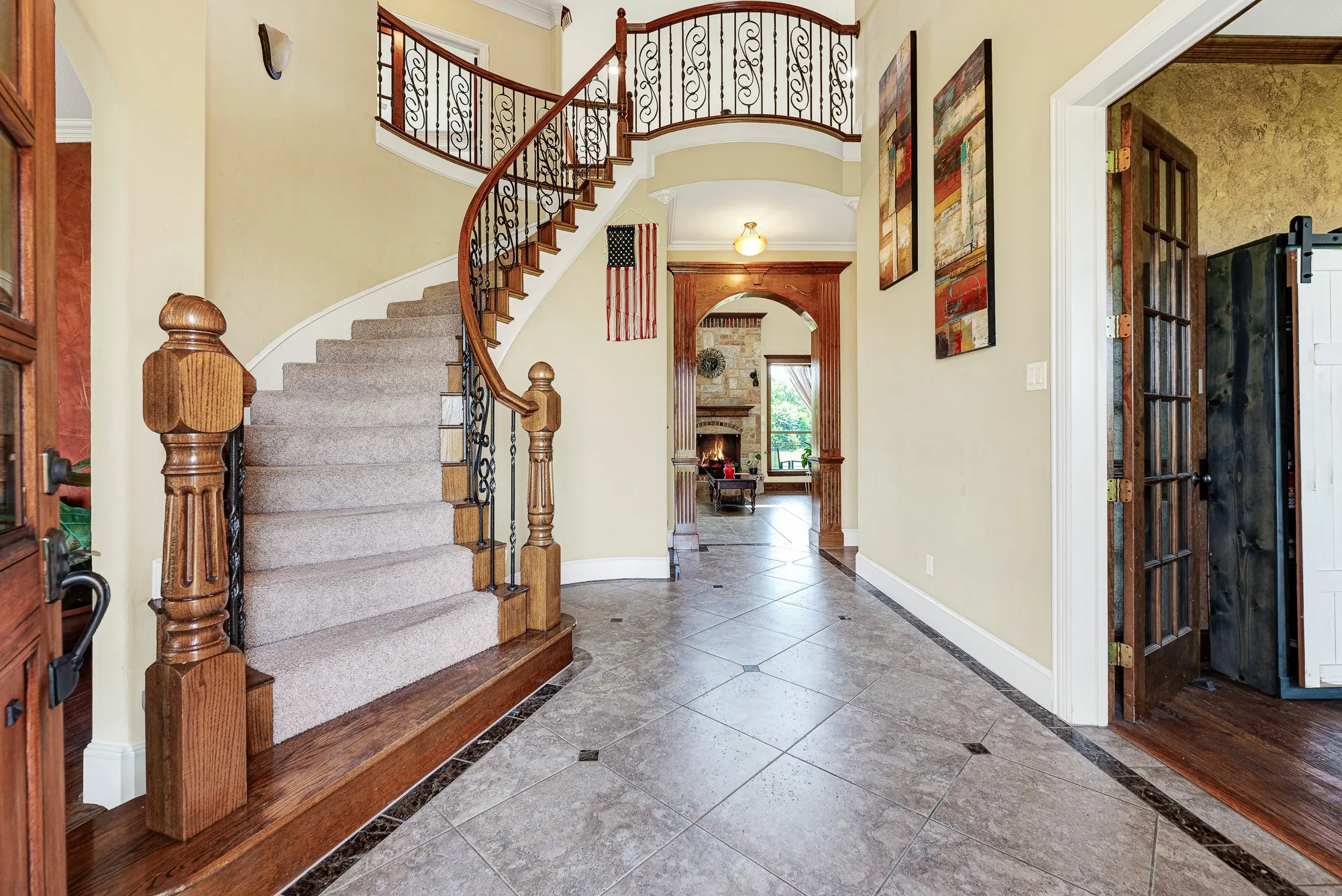 The sweeping, curved staircase draws the eye upward while a substantial wooden archway coaxes you deeper toward the cozy hearth beyond. Picture coming home after a long trip, stepping onto the polished tile, and instantly feeling wrapped in complete comfort.