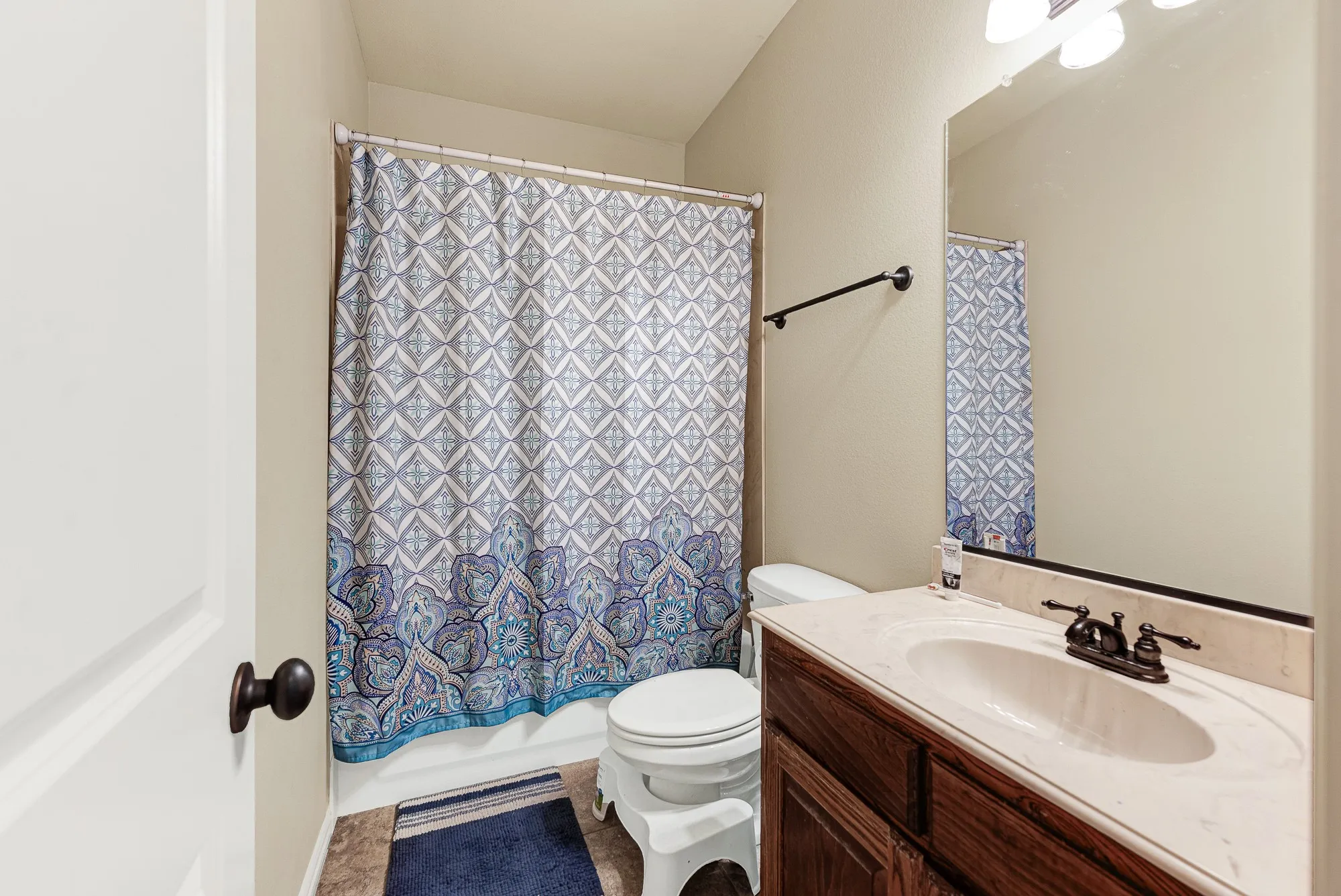 A traditional wood vanity with a stone-toned top pairs beautifully with dark plumbing fixtures. Imagine getting ready here for a busy day ahead, enjoying a private and functional space all to yourself.