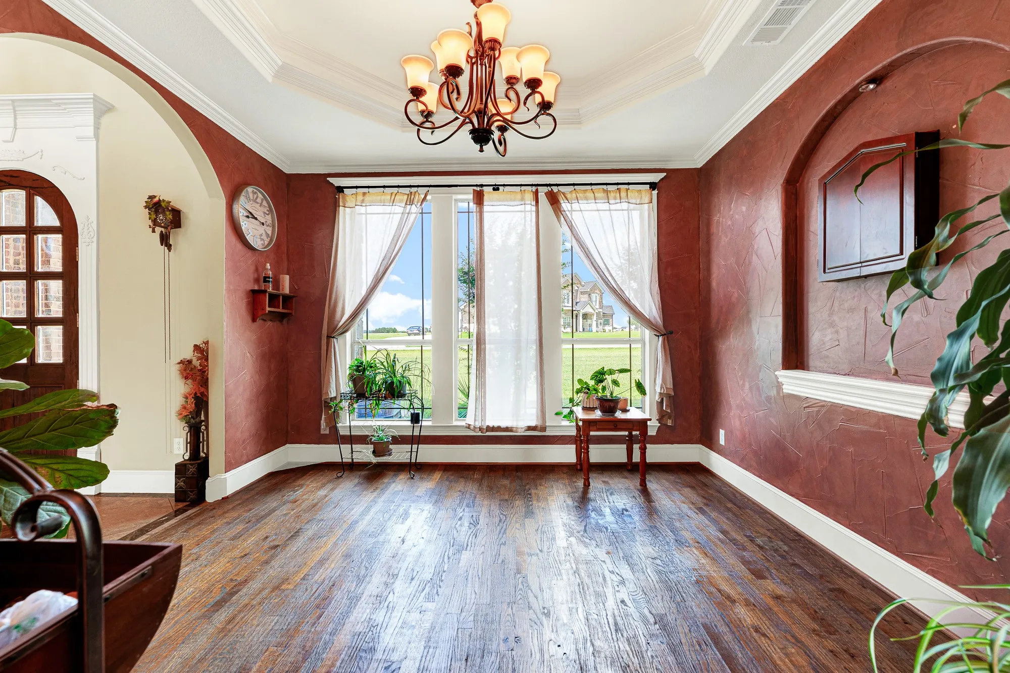 An elegant tray ceiling with crisp, multi-tiered crown molding draws the eyes upward, elevating the entire room's sense of scale. Picture hosting a candlelit dinner party here, where laughter echoes softly beneath the glow of the overhead chandelier.