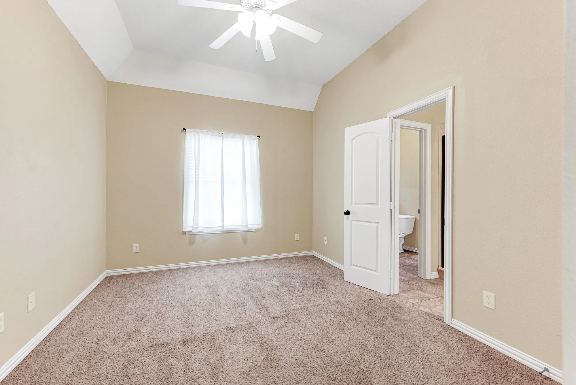 A classic tray ceiling adds subtle architectural depth, while an open doorway provides seamless flow directly into the adjoining bath. This layout makes it incredibly easy for guests to balance privacy with shared convenience