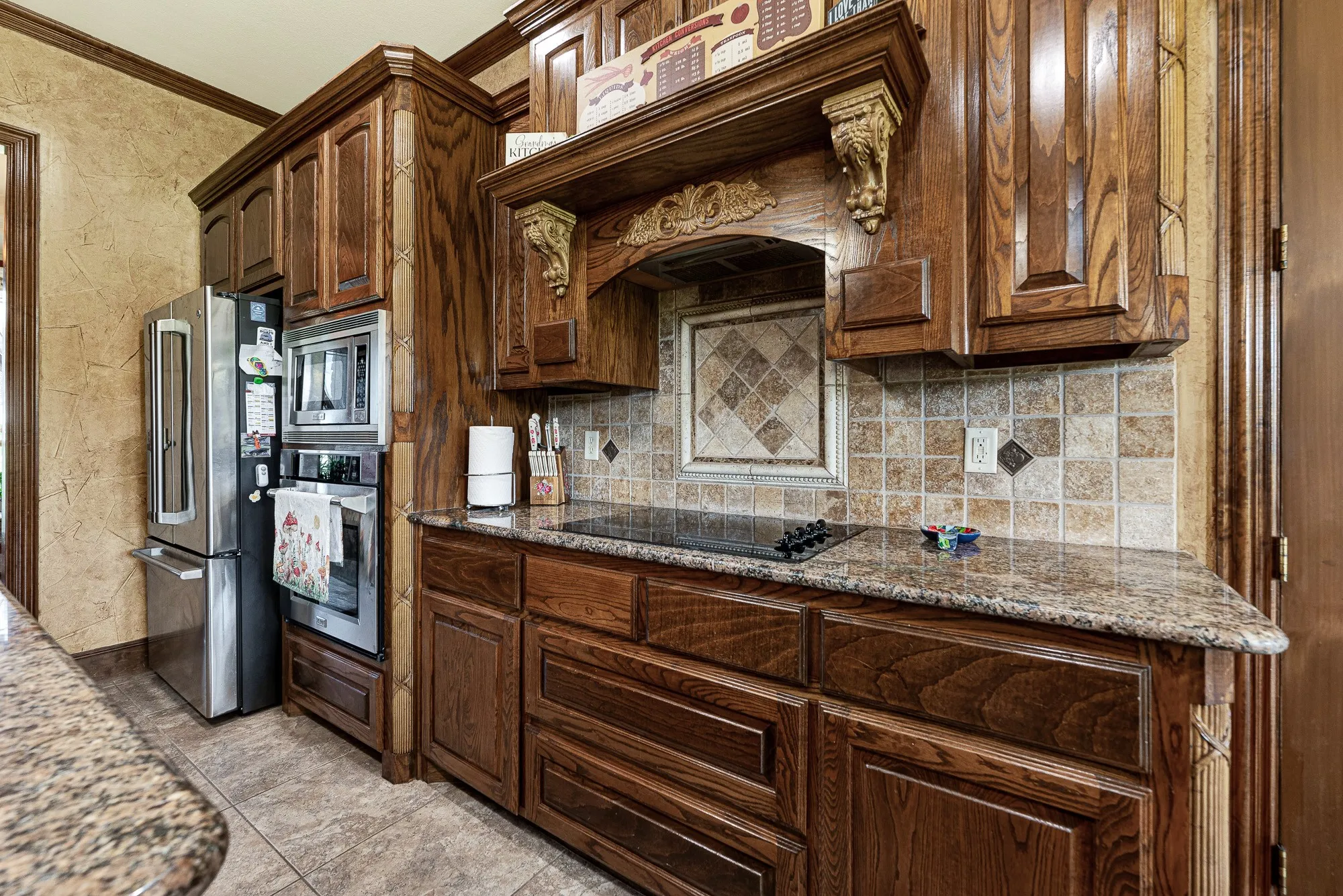 An ornate, hearth-style wooden mantle frames the cooktop, creating a deeply traditional and grounded architectural anchor. Picture the comforting aroma of a simmering Sunday sauce filling the air while you stir a favorite recipe over the stove.