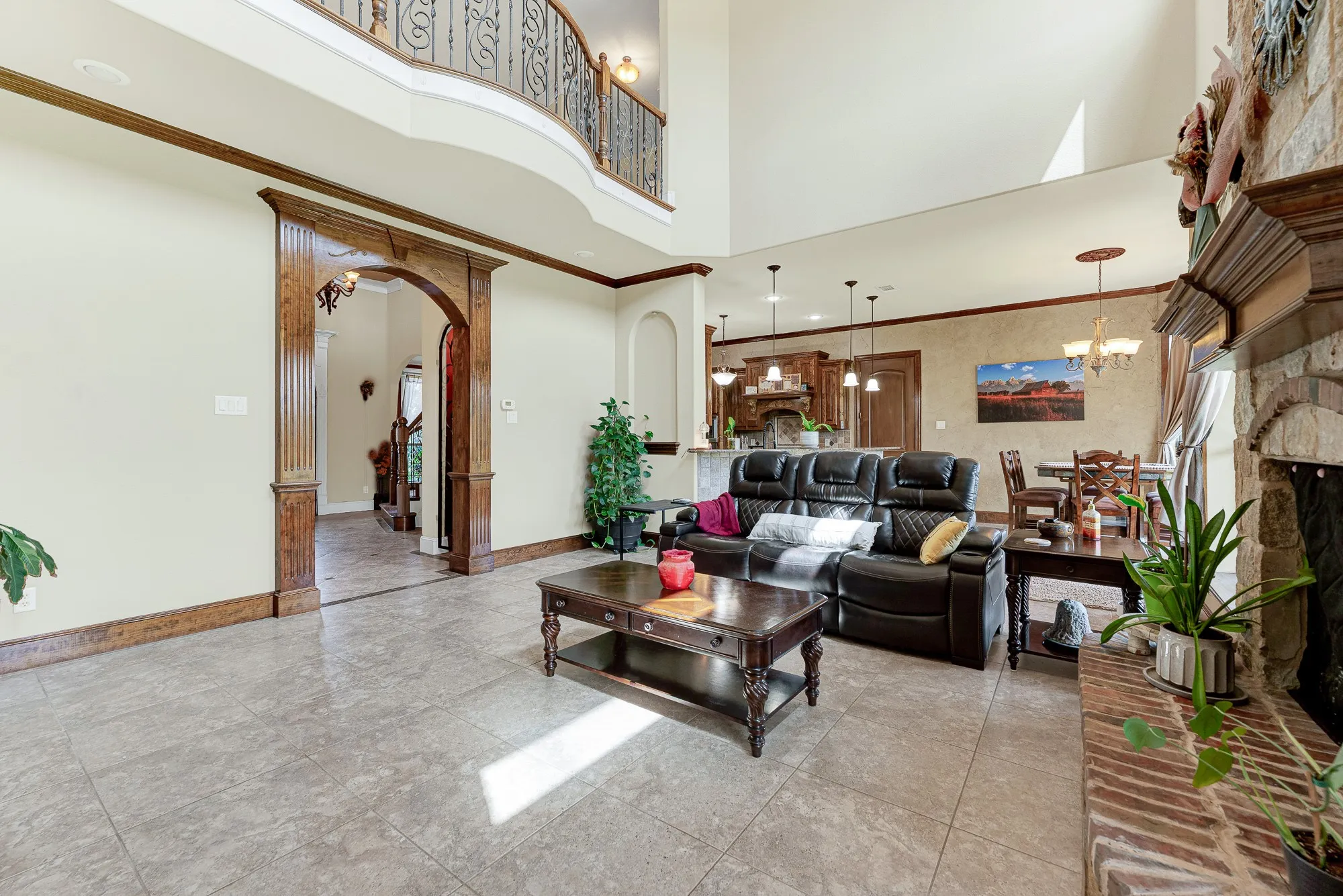 The dramatic, soaring double-height ceiling opens up beautifully to a curved second-story overlook with detailed iron balusters. Picture yourself relaxing here during a quiet rainy evening, enjoying the peaceful, airy volume of the home while a movie plays.