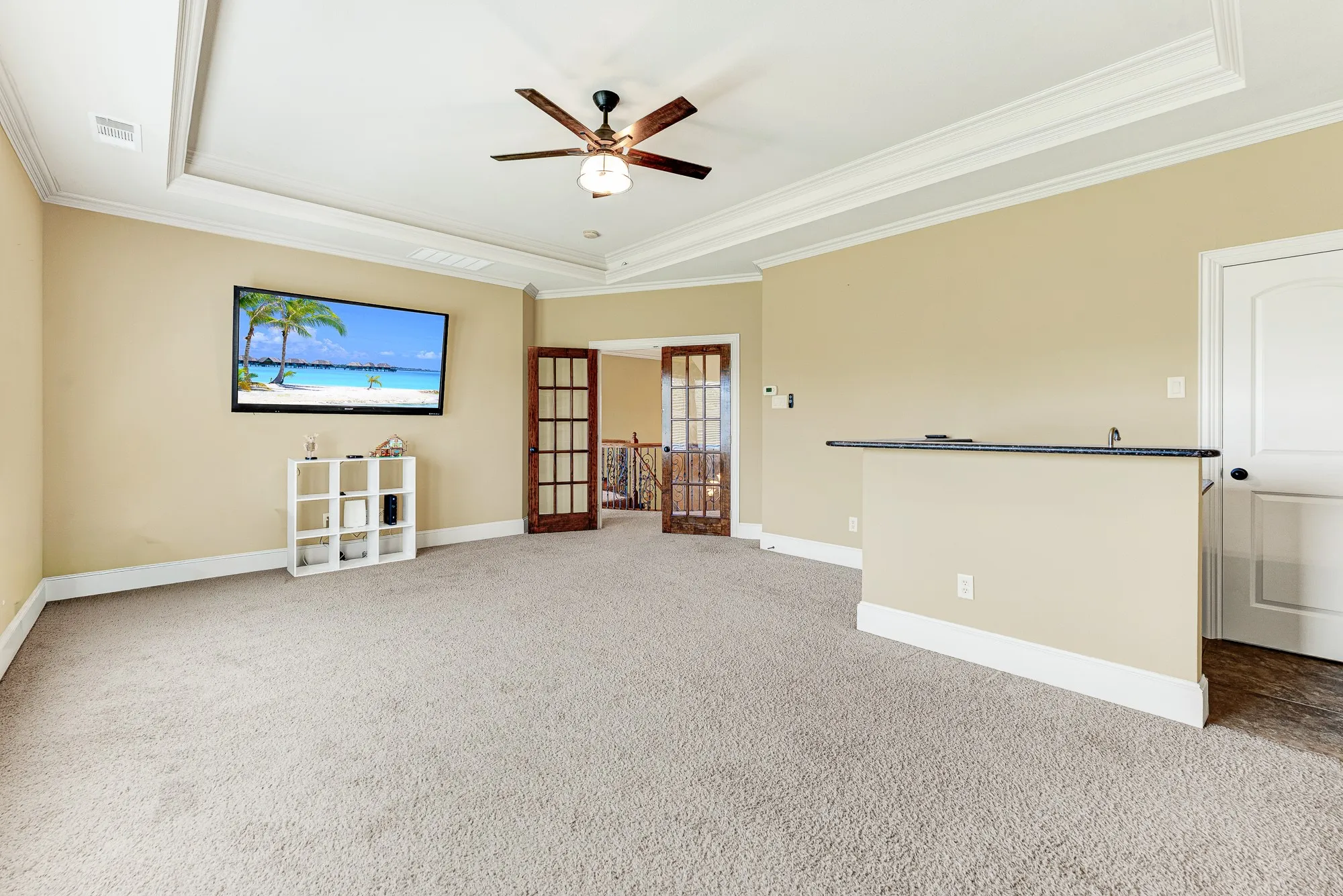 Double glass-paneled French doors frame a clear sightline to the staircase overlook, creating an airy sense of connection to the lower level. Picture hosting a casual game night where guests can easily drift between the main living area and this upstairs retreat.