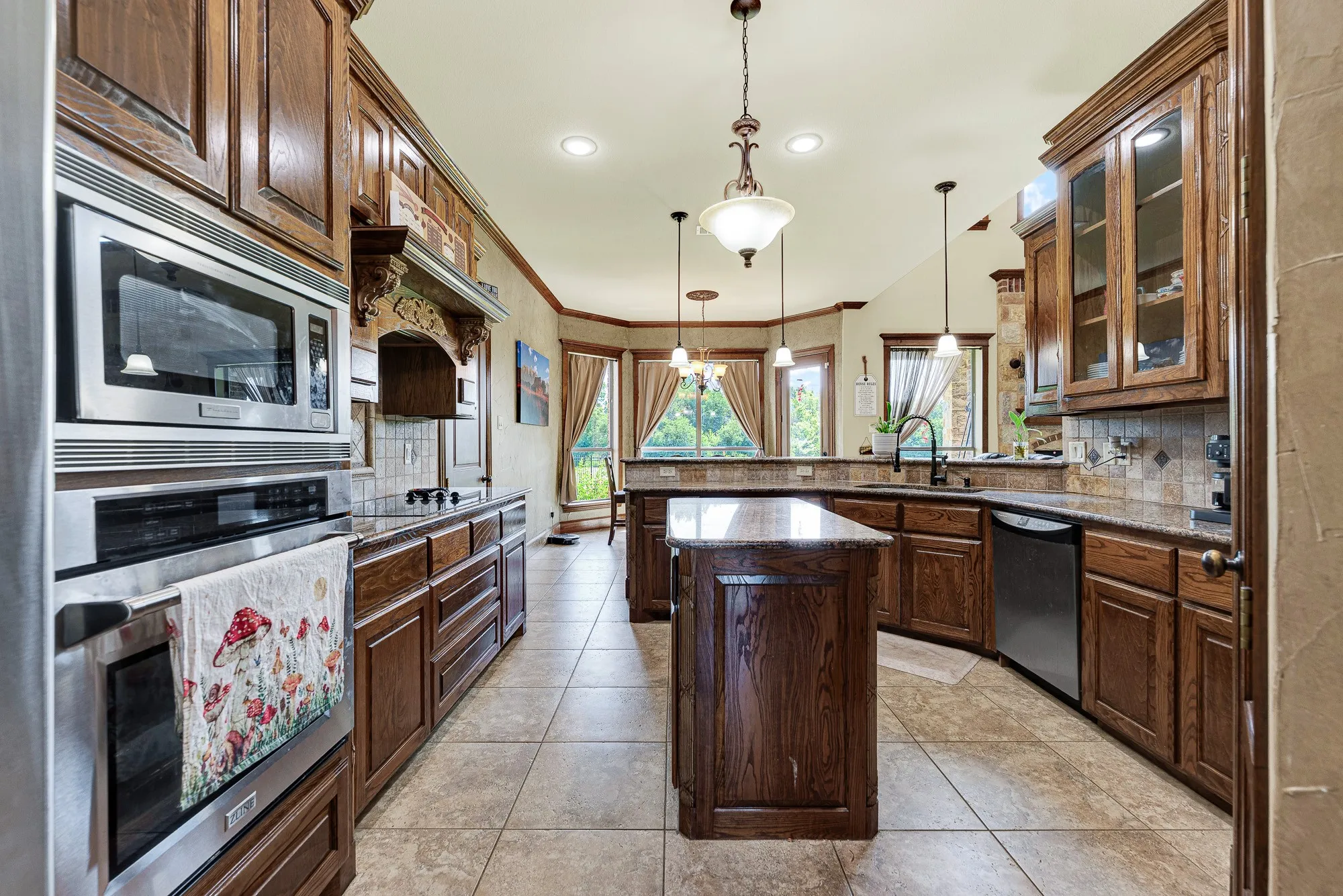 Richly toned wood cabinetry stretches toward a central prep island, perfectly balancing the expansive tile floors. Imagine unpacking groceries with ease, spreading ingredients across the smooth granite surfaces as you prepare a weekend feast.