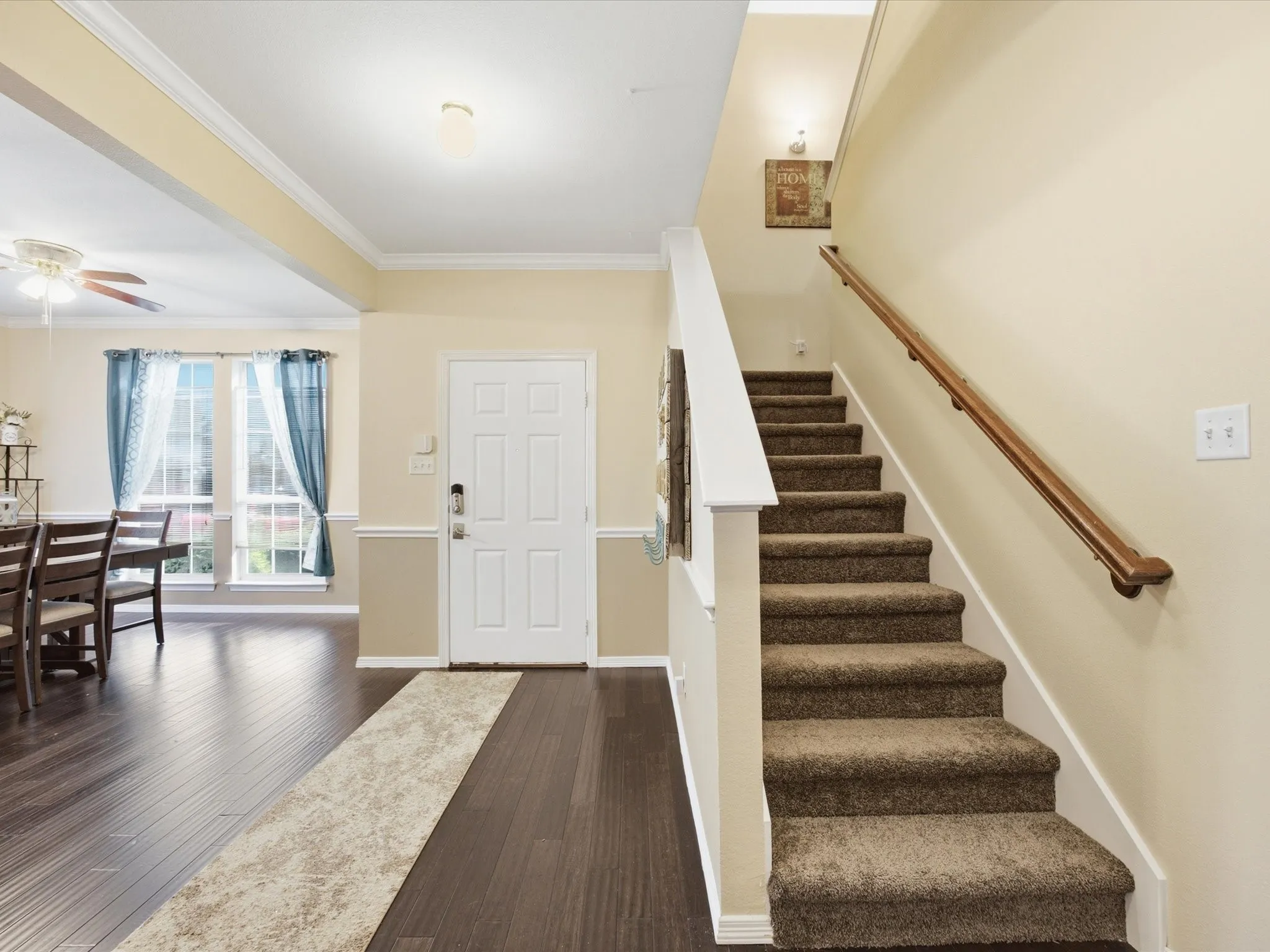 Entryway featuring wood-finish flooring, a carpeted staircase with a wood handrail, and a paneled white entry door