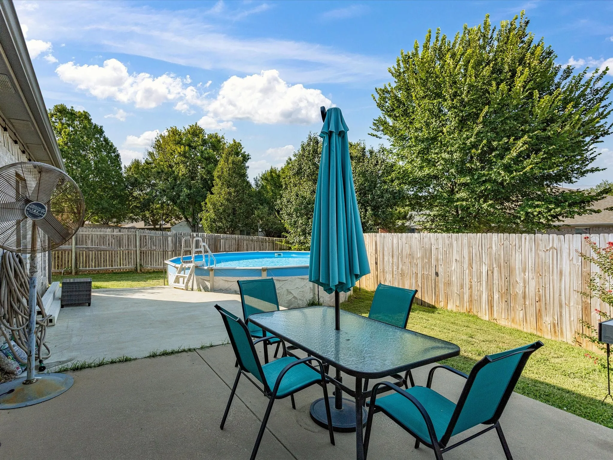 Private backyard featuring an above-ground pool, concrete patio, and wood privacy fencing