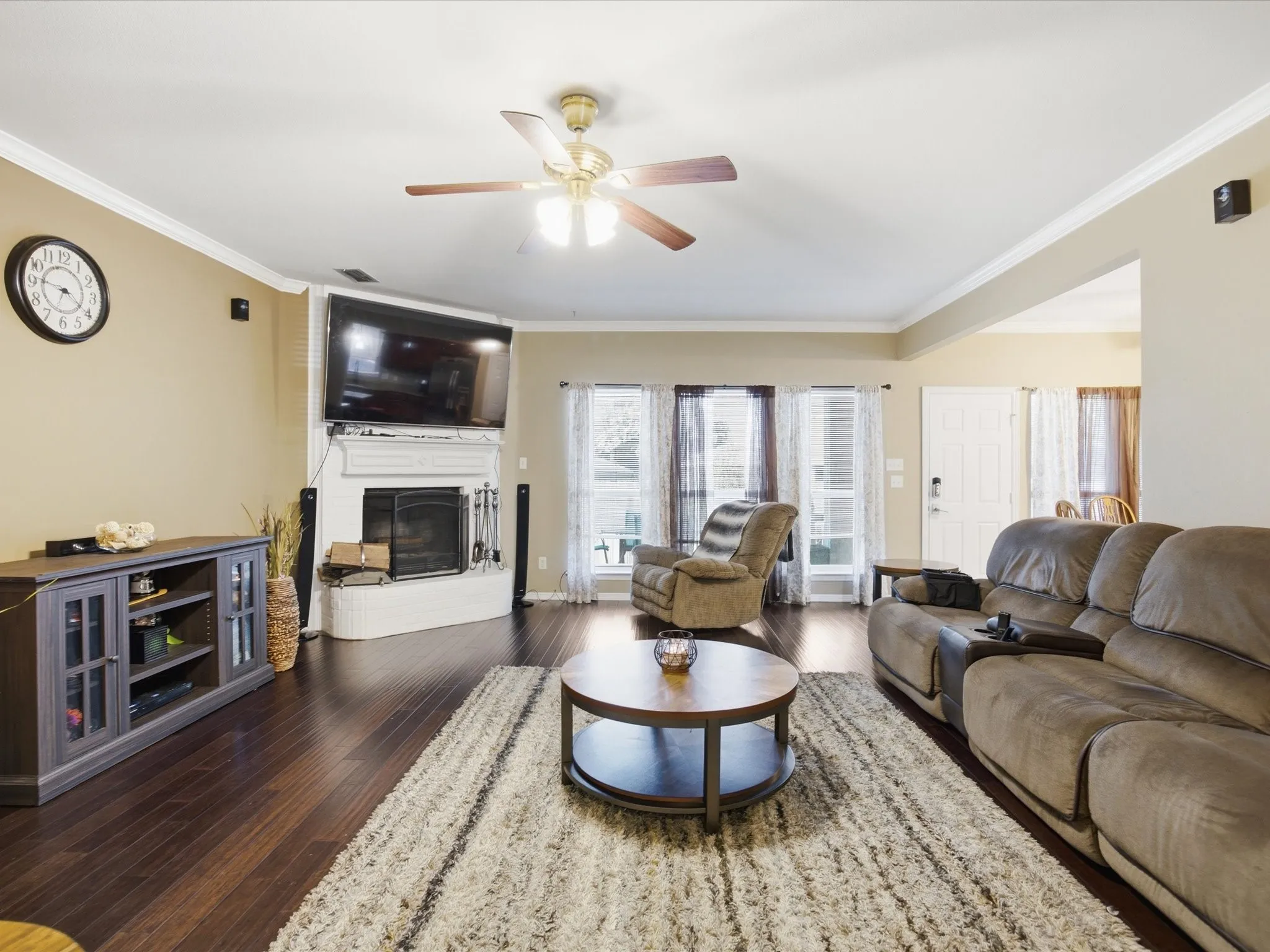 Living space featuring rich wood-finish flooring and a fireplace with a white mantel and hearth