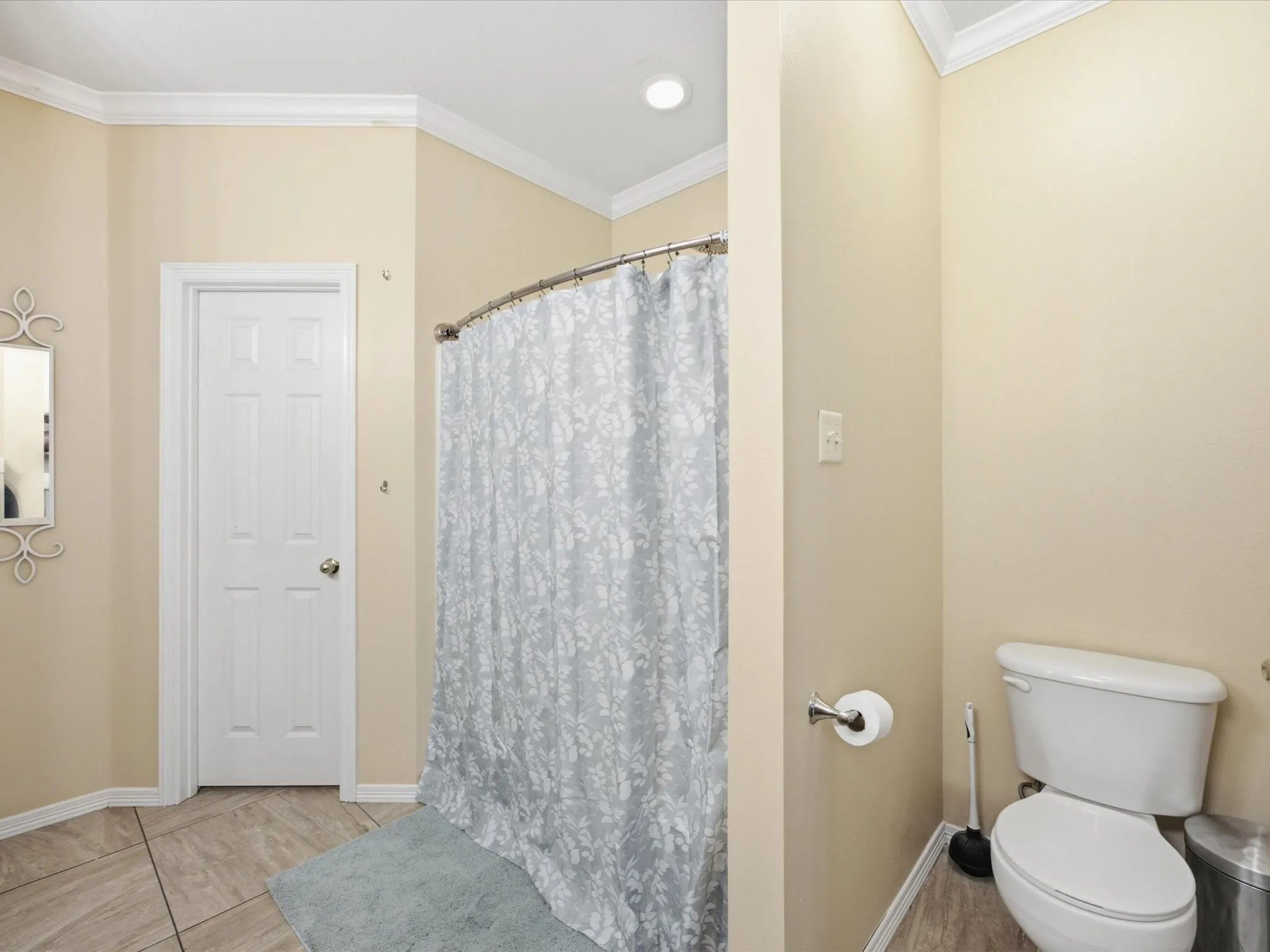 Primary Bathroom featuring a white paneled door, a standard toilet, and neutral-toned wall paint