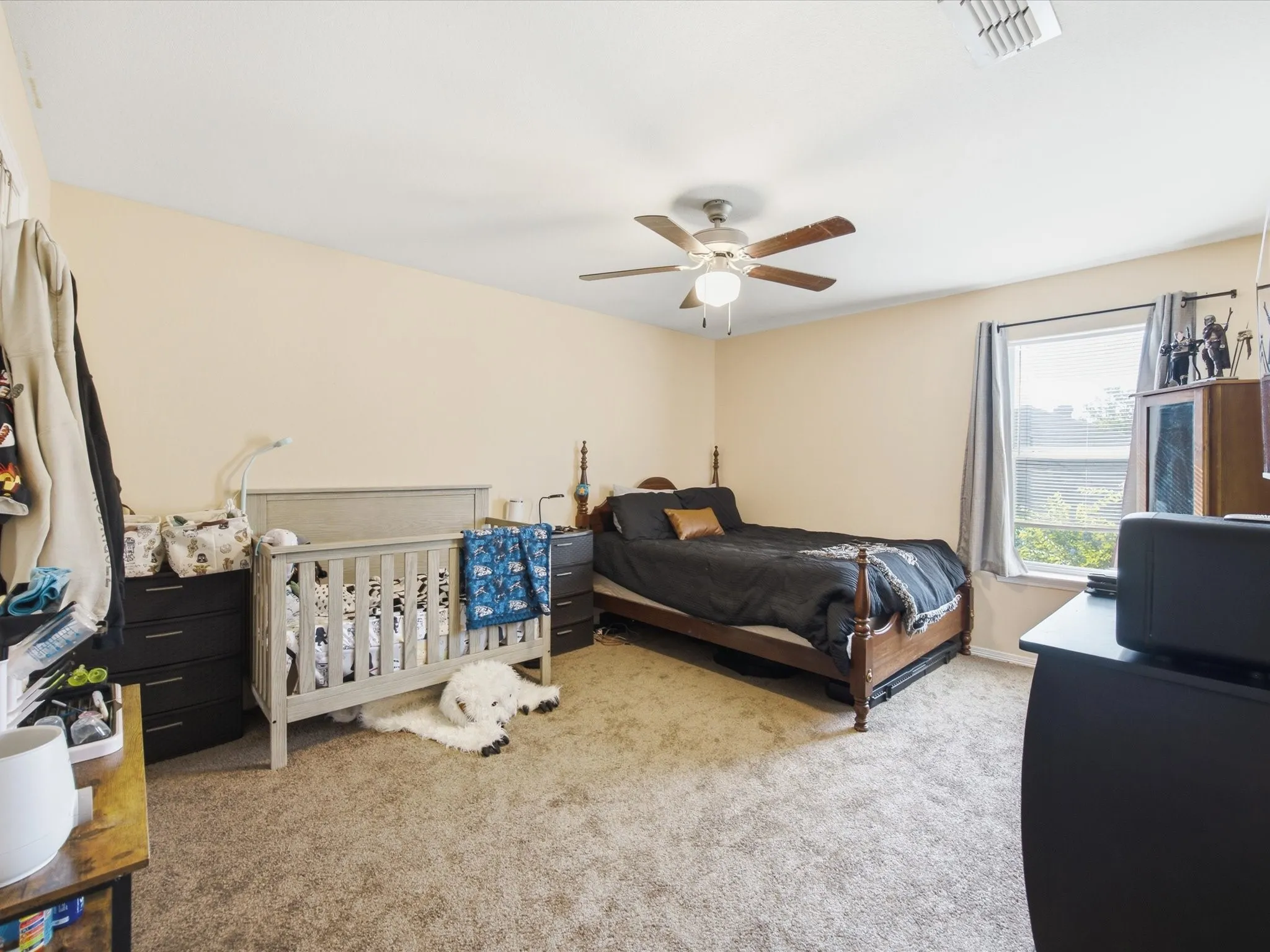 Carpeted bedroom with a single window, a ceiling fan with integrated lighting, and neutral-toned walls