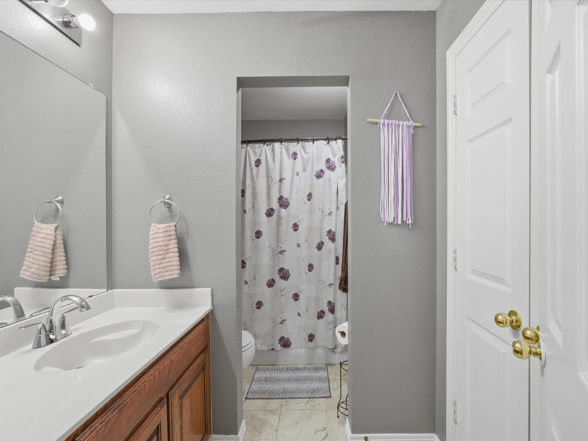 Bathroom featuring a wood-finish vanity with a white countertop, chrome faucet, and integrated sink
