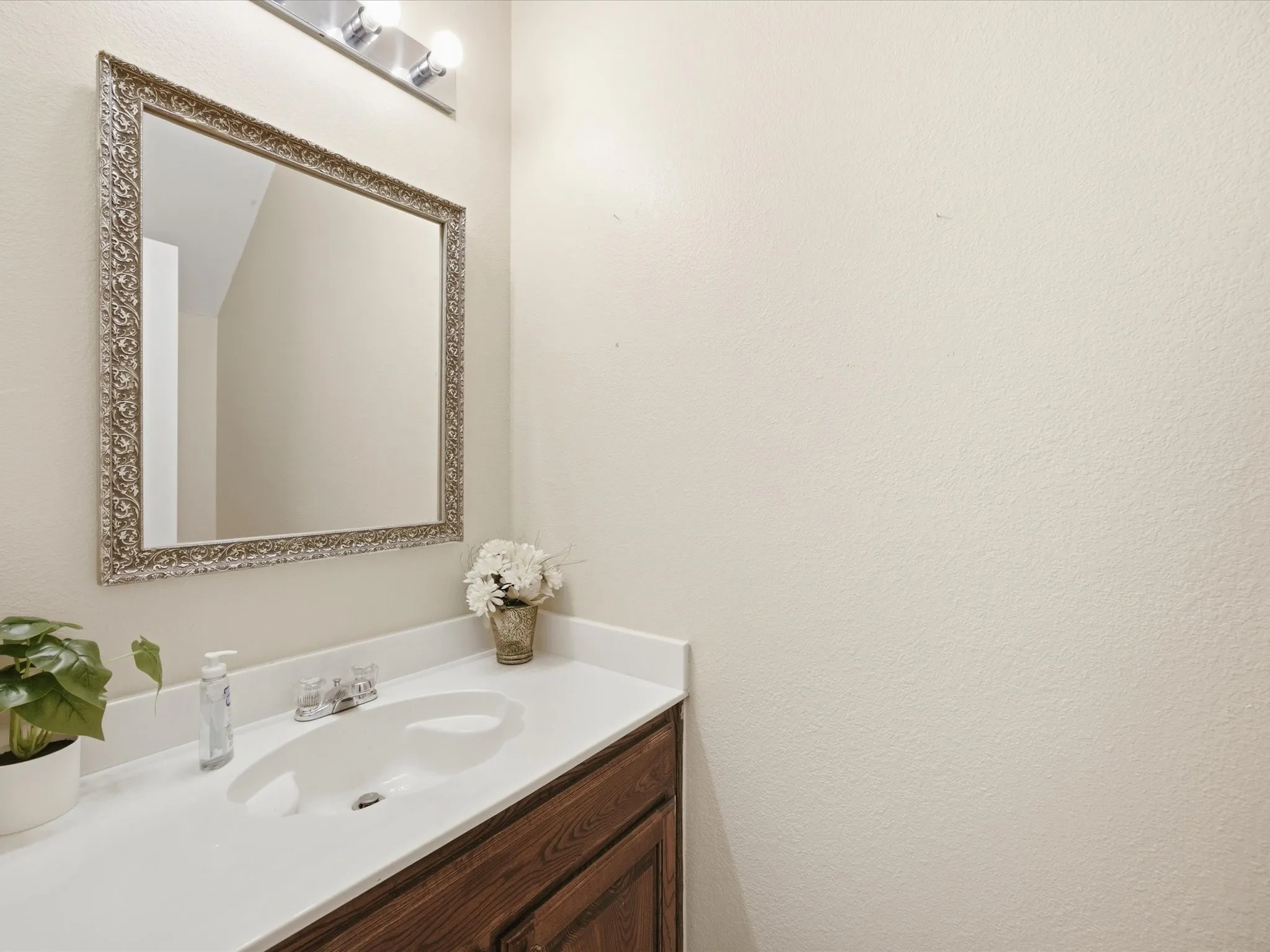 Vanity area featuring a framed mirror, a white countertop with an integrated sink, a two-handle faucet, and wood-finish cabinetry