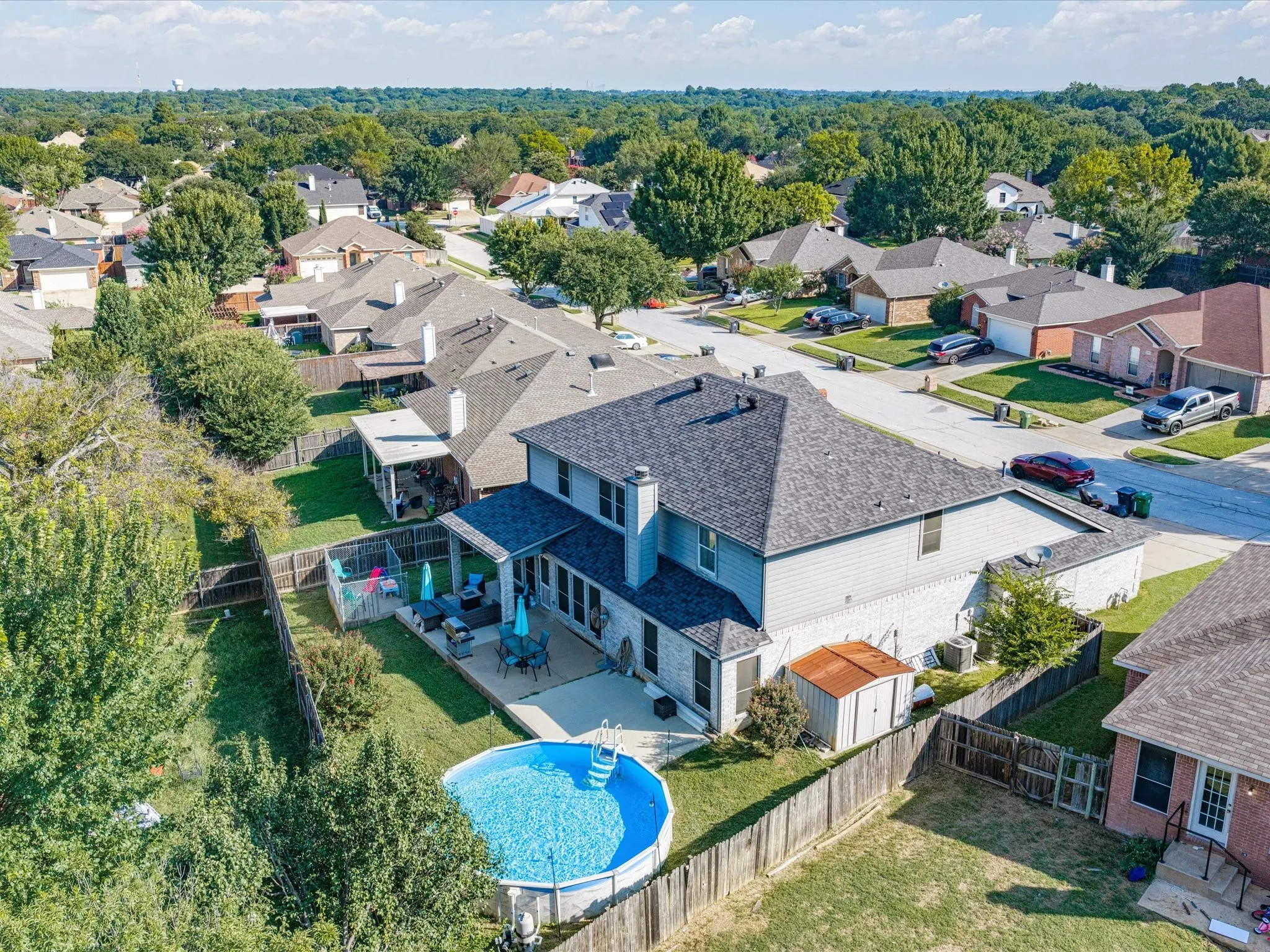Rear exterior featuring a above-ground pool, covered patio, fenced yard, and a storage shed