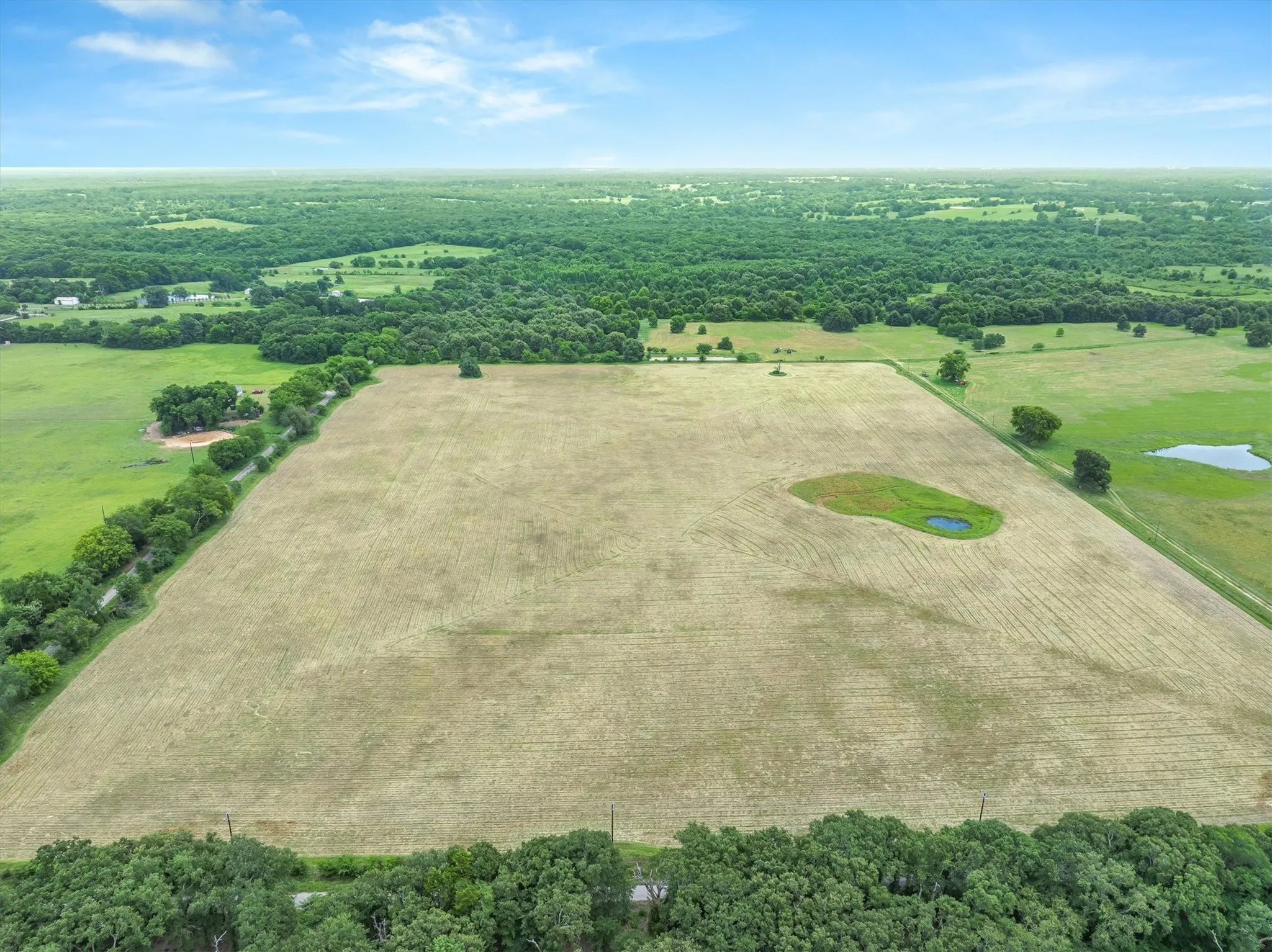 Expansive agricultural land featuring a central pond
