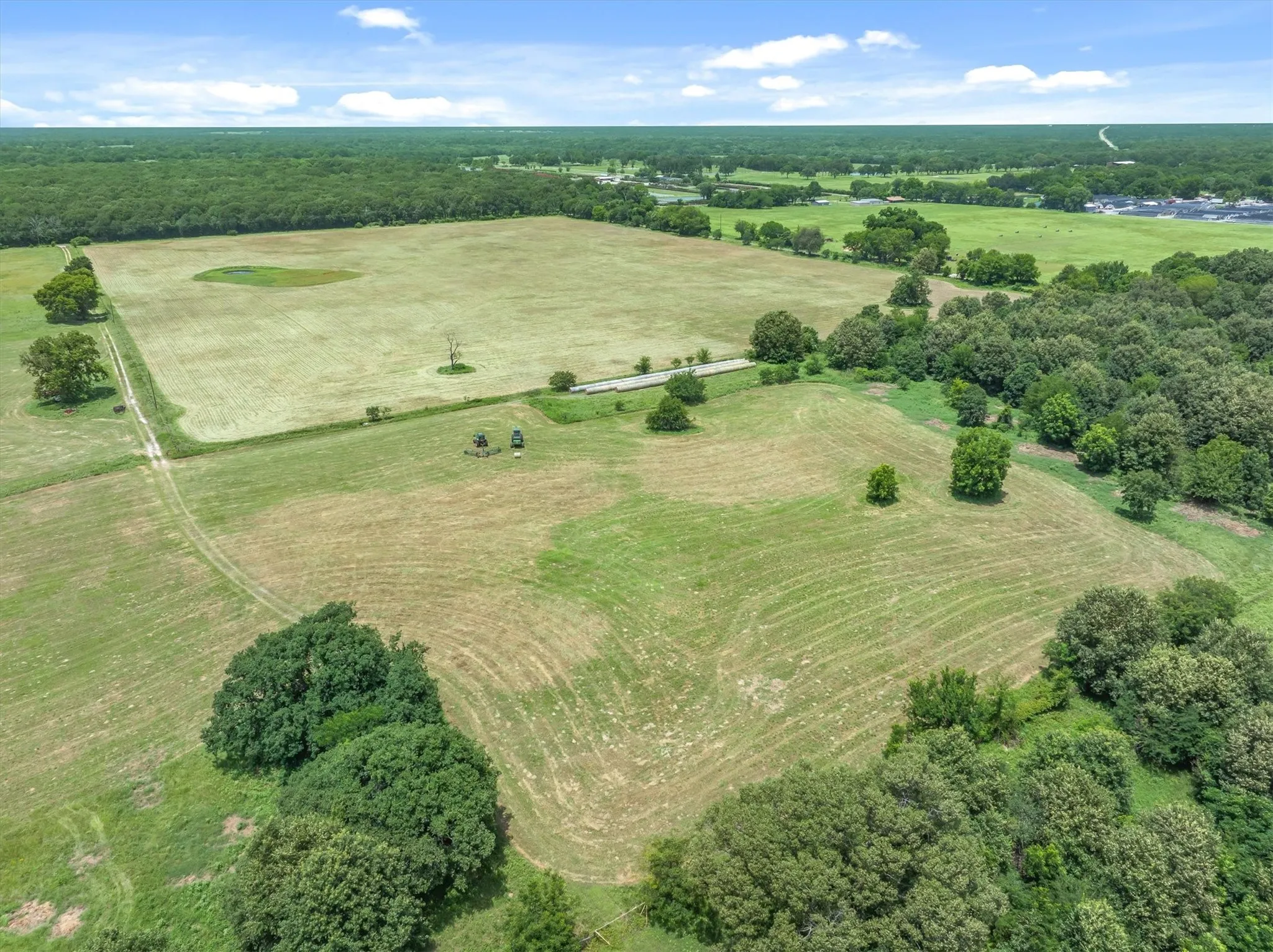 Expansive agricultural land featuring a mix of cleared fields and mature tree lines