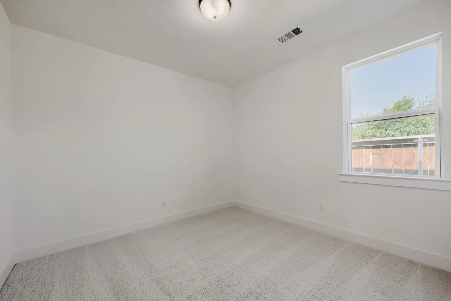 Carpeted room featuring a single window, white walls, and a flush mount ceiling light