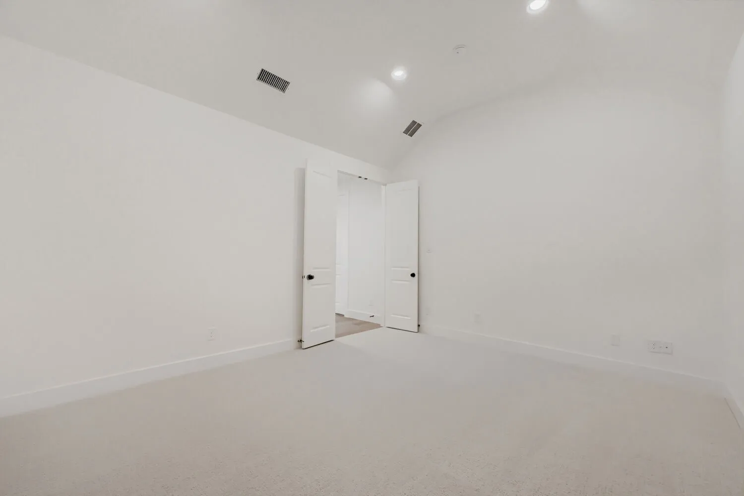 Spacious room featuring vaulted ceilings, light-toned carpeting, recessed lighting, and white baseboards