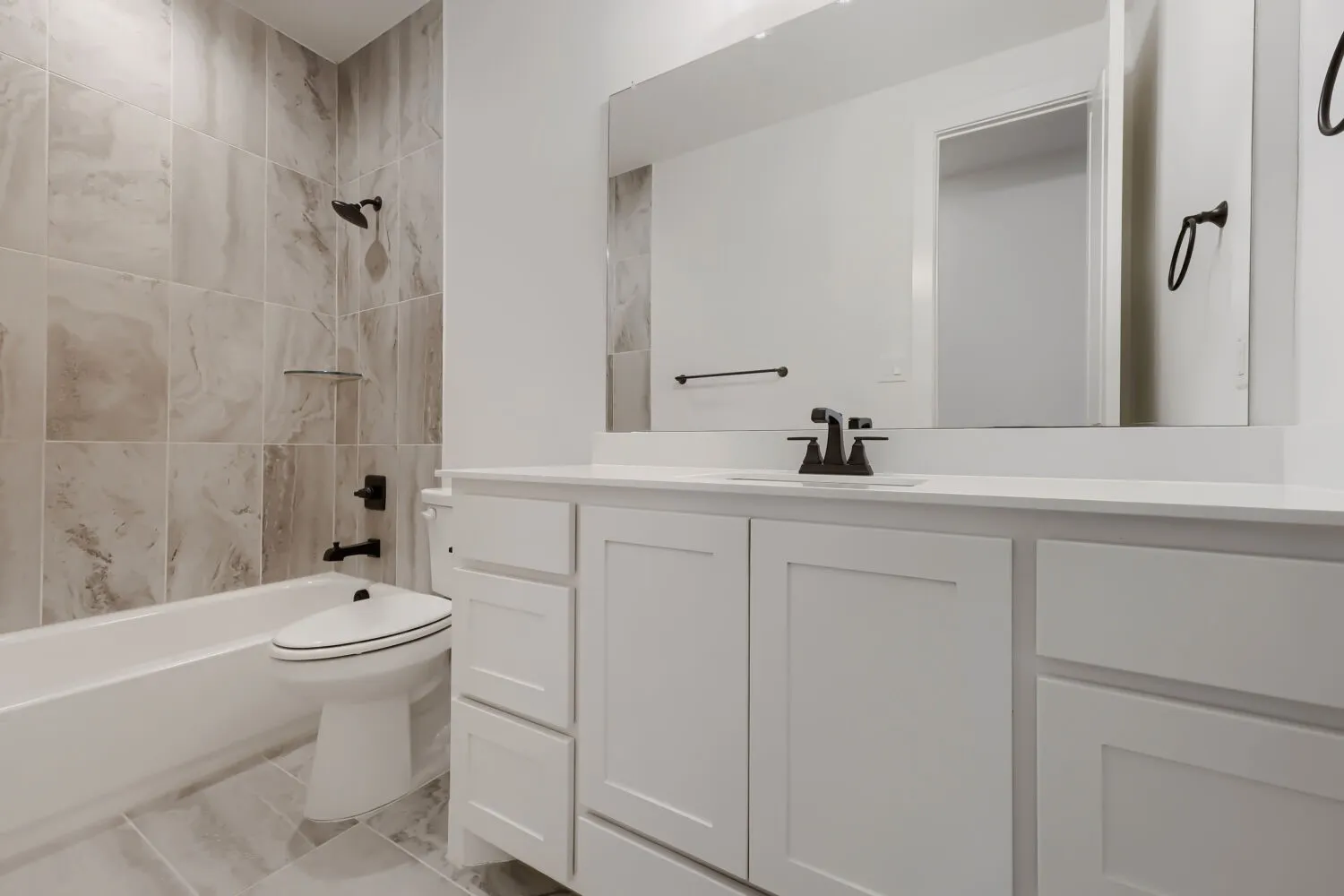 Bathroom featuring a white vanity with slab-front drawers and shaker-style cabinet doors, a white countertop, and a large mirror