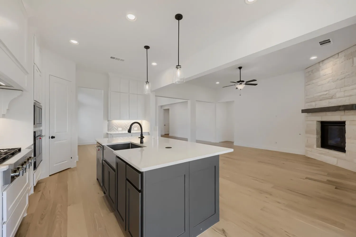 Modern kitchen island with a farmhouse sink, white countertops, and pendant lighting