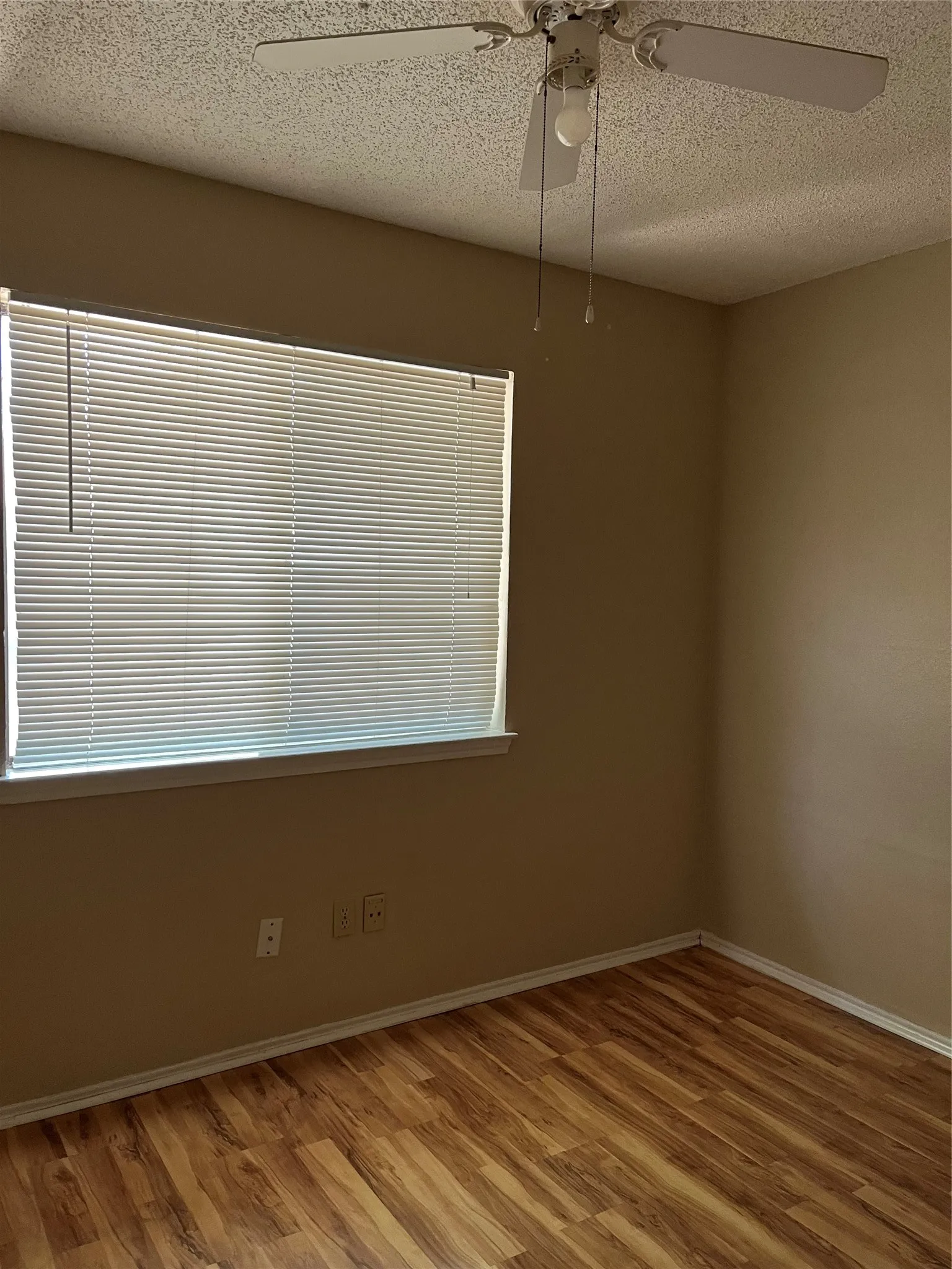 Room featuring wood-finish flooring, neutral wall paint, and a textured ceiling