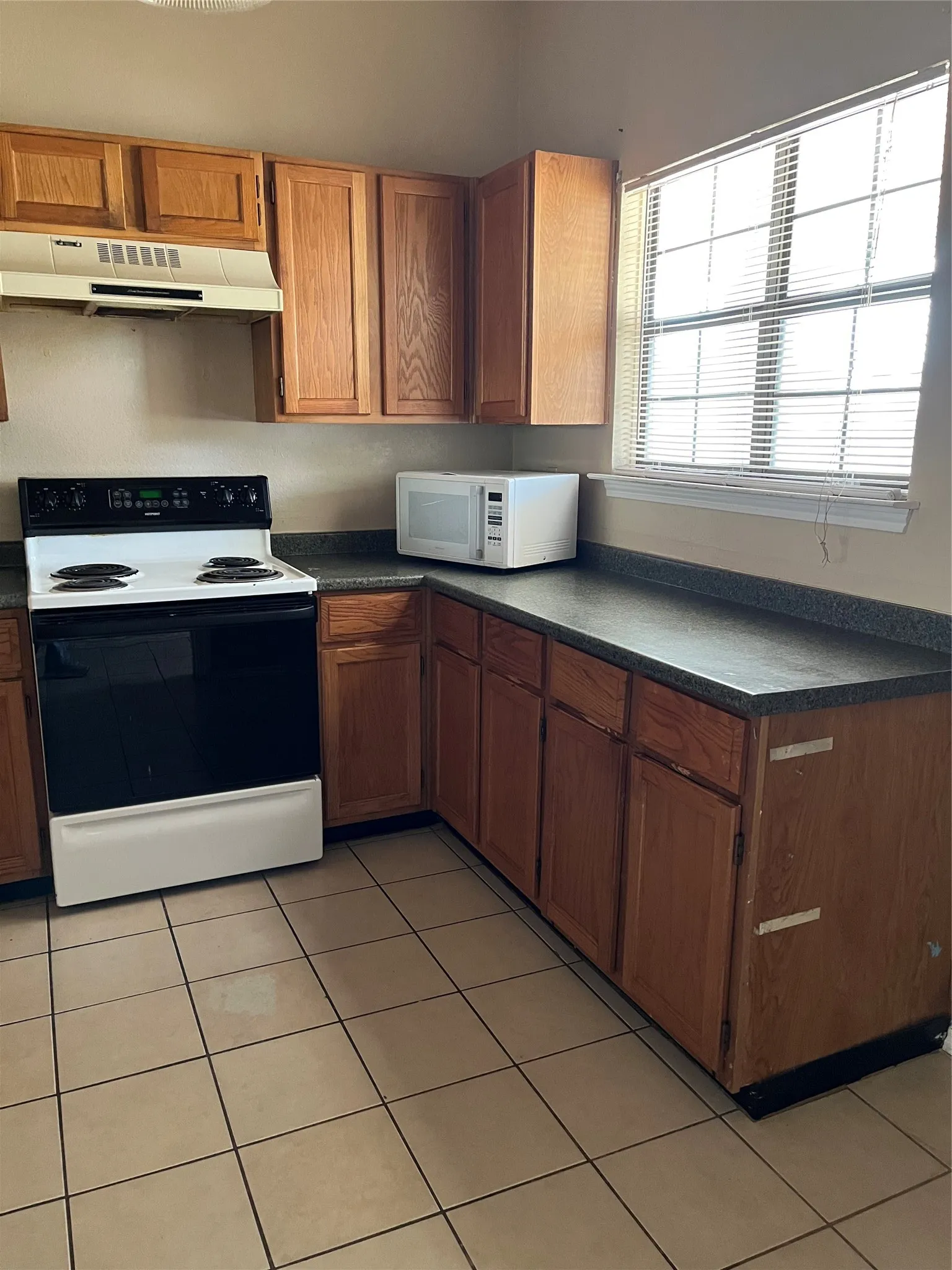 Kitchen featuring wood-finish cabinetry, dark countertops, and a white electric range