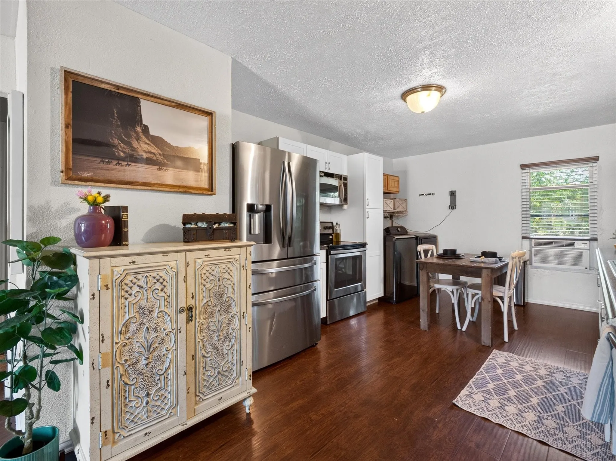 Kitchen space featuring wood-finish flooring, stainless steel refrigerator, stainless steel range, built-in microwave, and white cabinetry