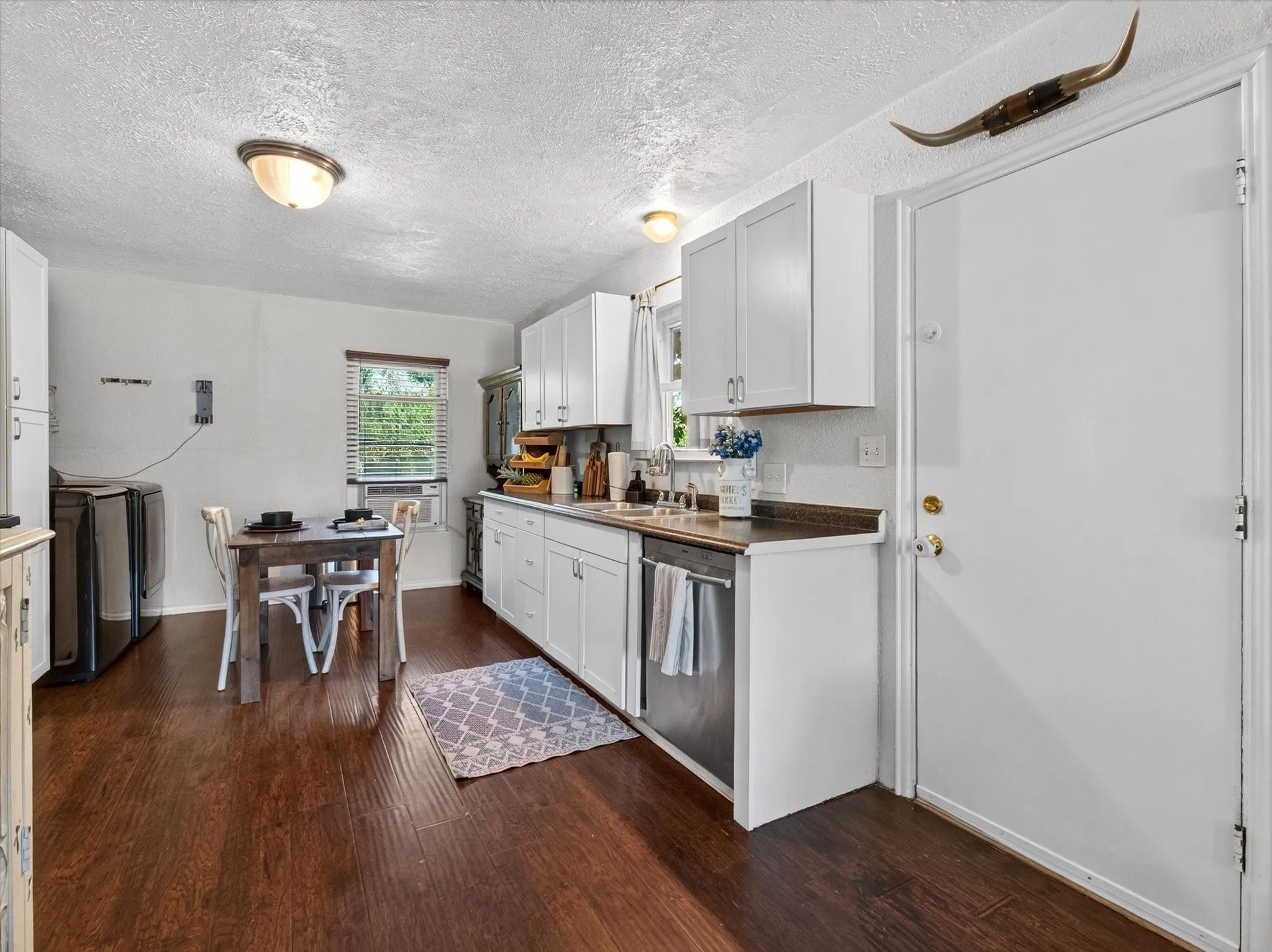 Kitchen featuring wood-finish flooring and white cabinetry