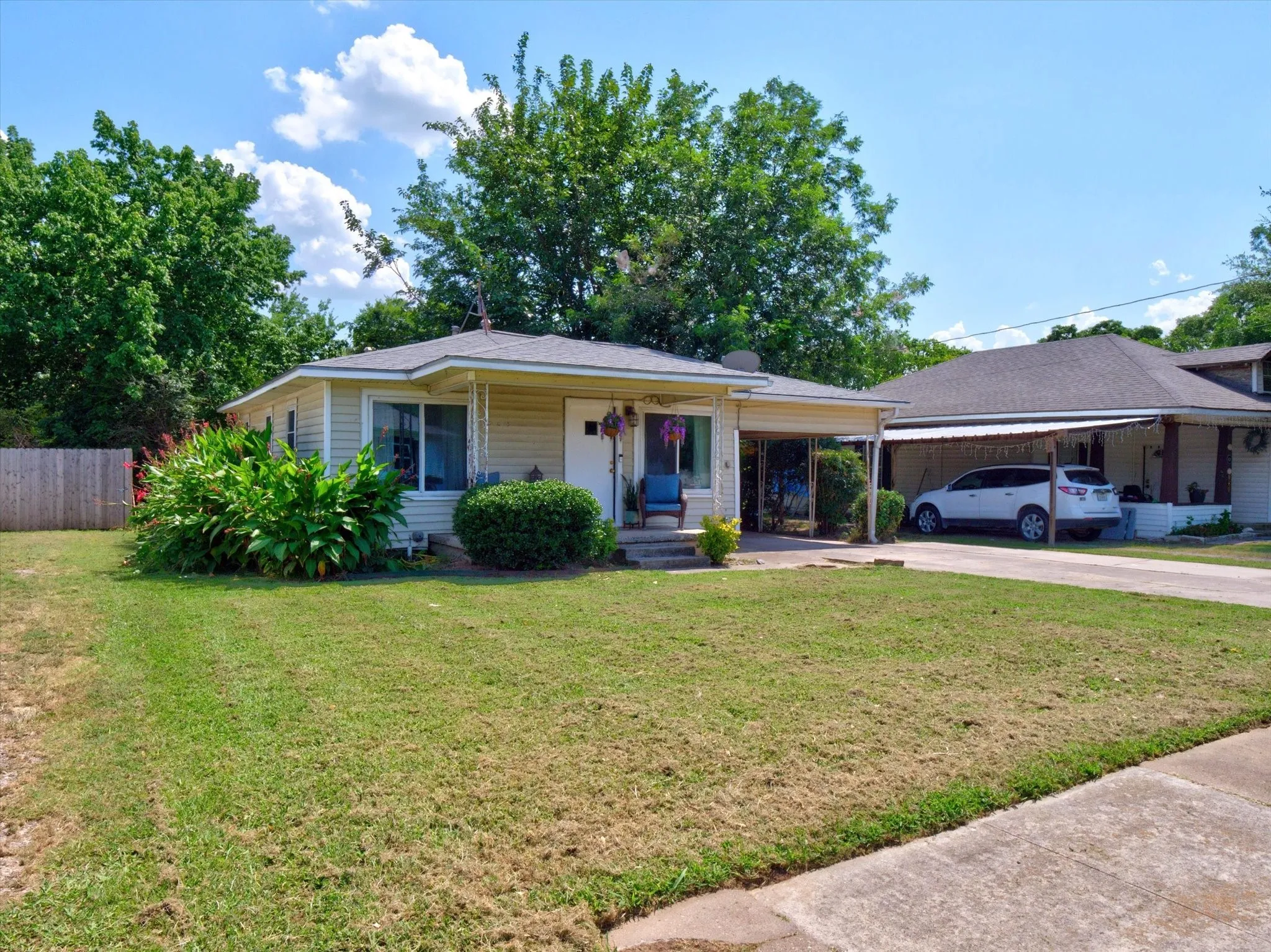 Single-story residence featuring light-colored siding, a covered front entry, and a covered carport with a concrete driveway