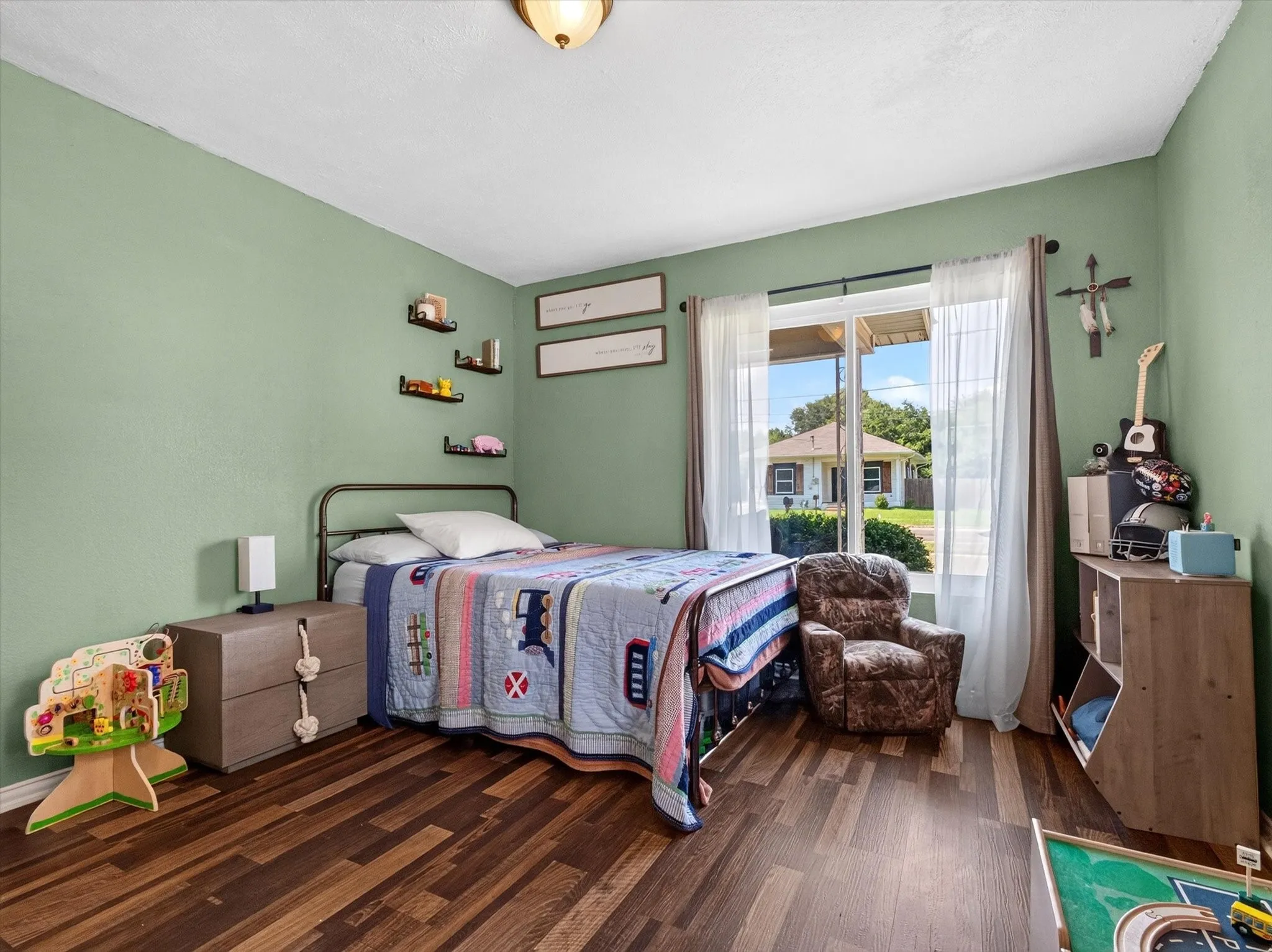 Spacious room featuring wood-finish flooring, a contemporary ceiling light fixture, and a large window providing ample natural light