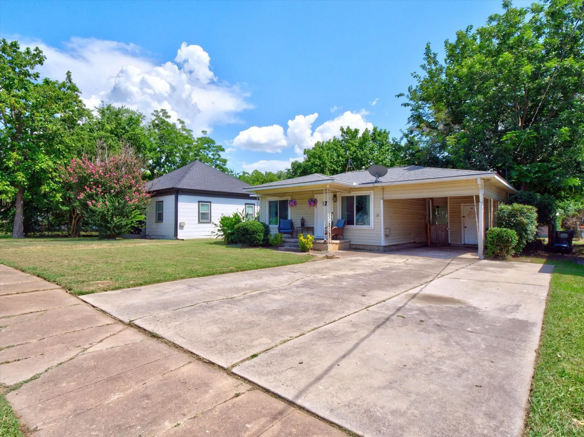 Single-story residence featuring light-colored siding, a covered carport, and a concrete driveway