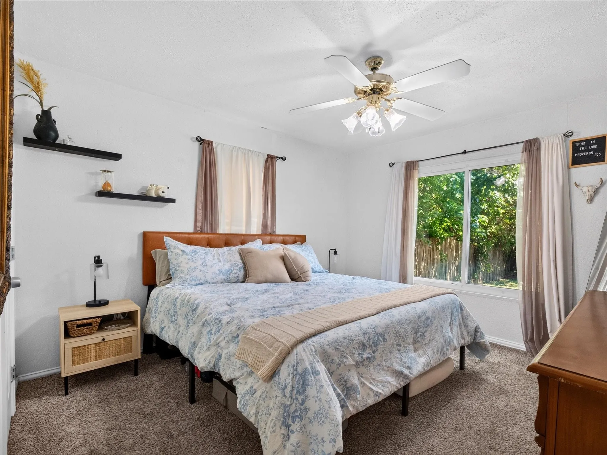 Bedroom featuring a large window, neutral carpeting, and a ceiling fan with integrated lighting