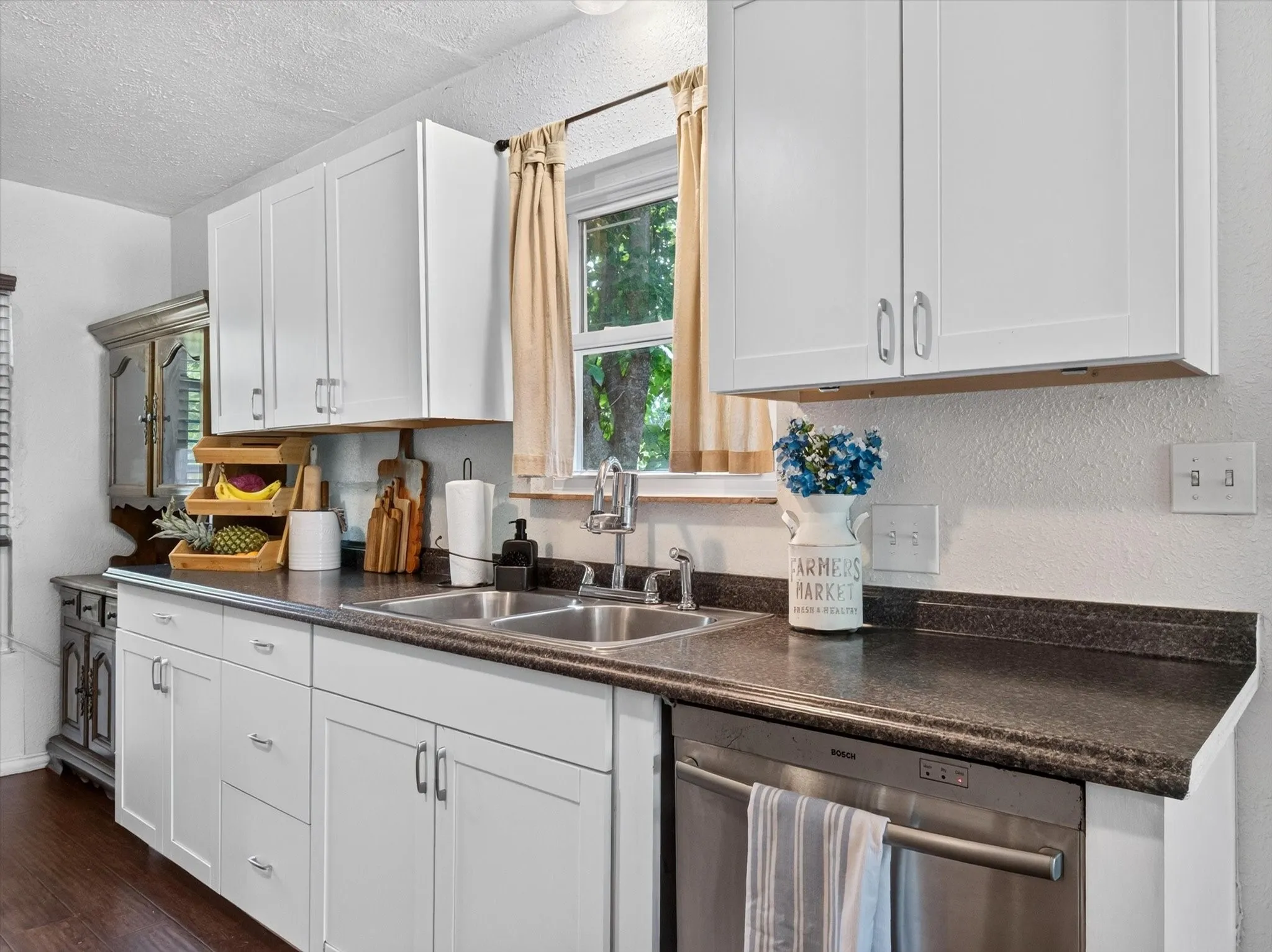 Kitchen featuring white shaker-style cabinetry, dark speckled countertops, and a double basin stainless steel sink with a gooseneck faucet