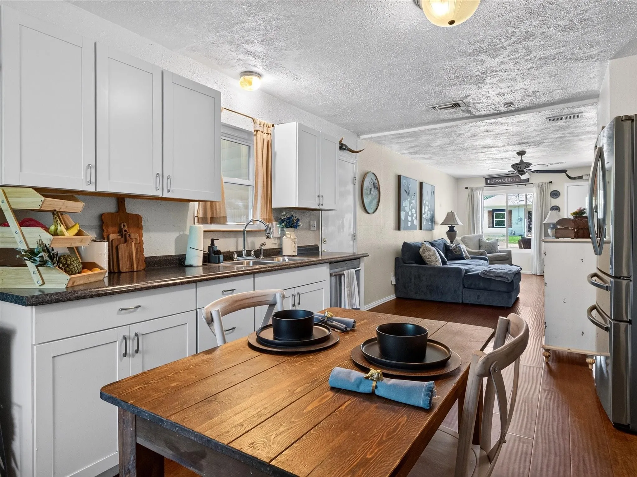 Kitchen featuring white shaker-style cabinetry, dark countertops, and a stainless steel sink