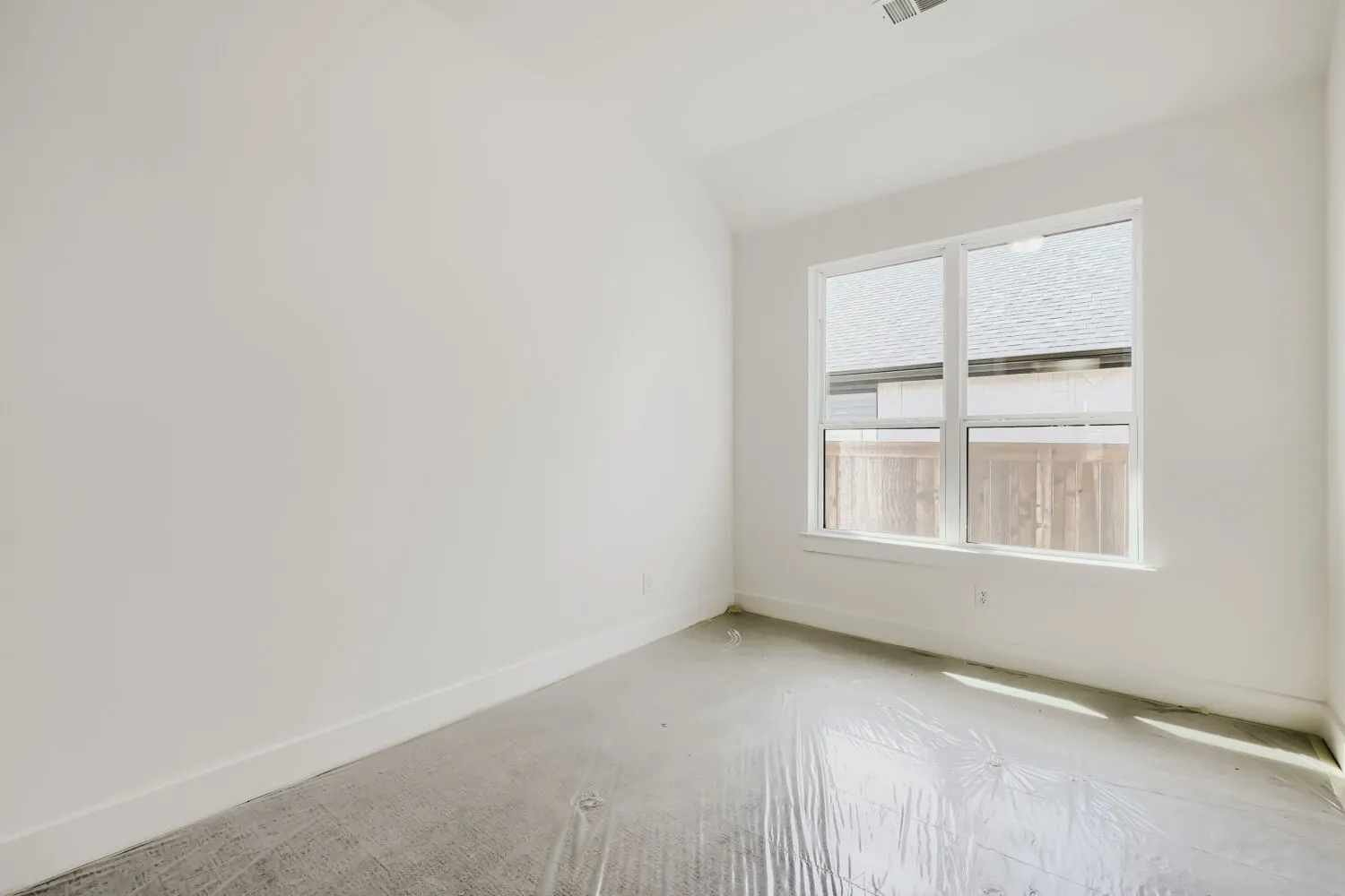 Room featuring an egress window, white walls, white trim, and a high ceiling