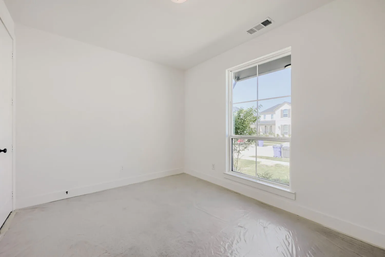Bright interior room featuring a large window, white walls, and white trim