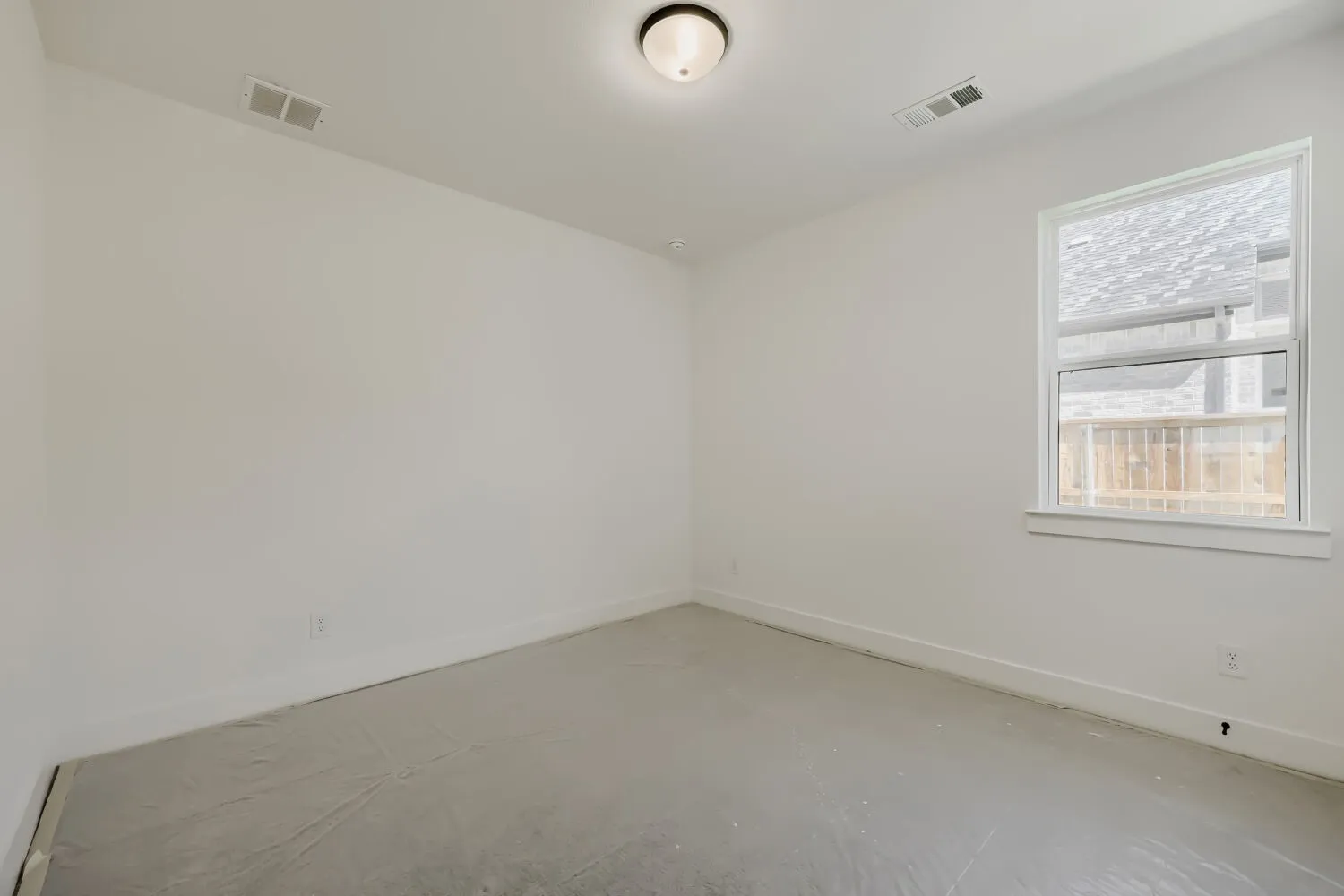 Spacious room featuring a single window with white trim, a flush-mount ceiling light fixture, and white painted walls