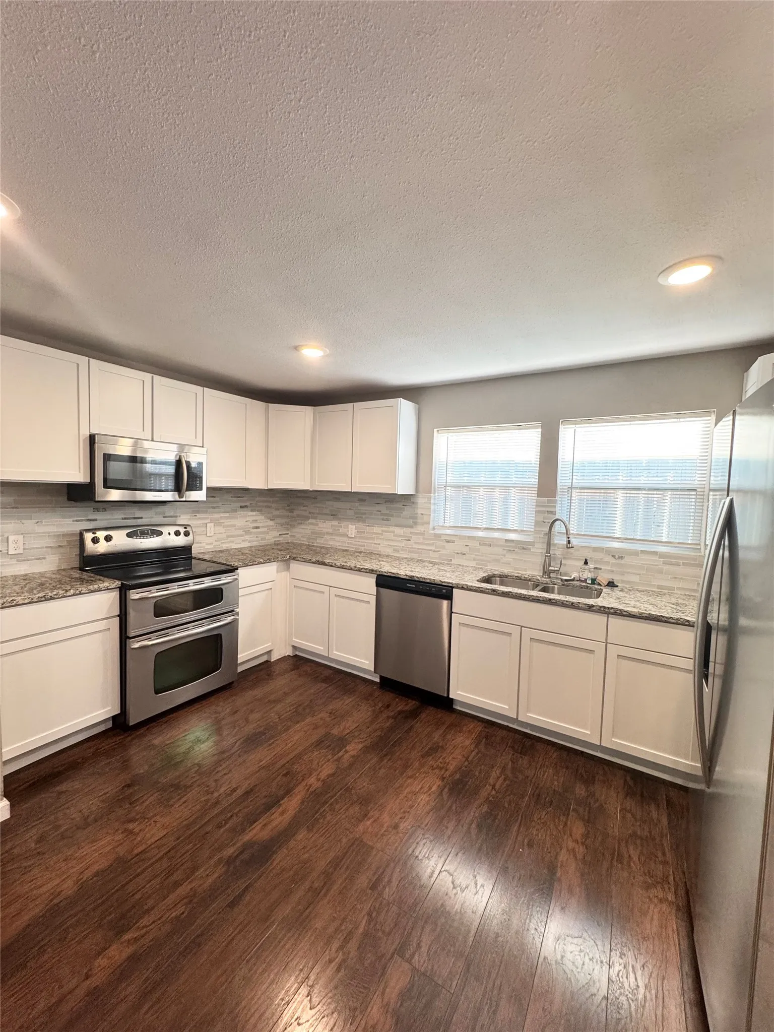 Kitchen featuring wood-finish flooring, white cabinetry, and stainless steel appliances