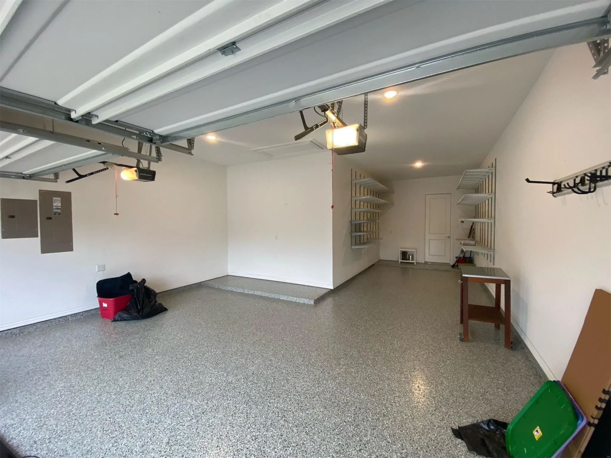 Spacious garage featuring a durable epoxy-coated floor, integrated shelving systems for organized storage, and recessed ceiling lighting