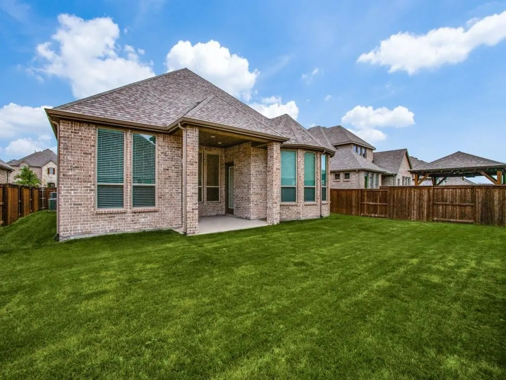 Expansive backyard featuring a lush lawn, a covered concrete patio, and a wood privacy fence