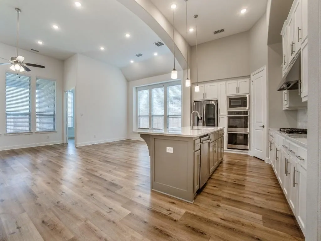 Open-concept living space featuring wood-finish flooring, recessed lighting, and a vaulted ceiling