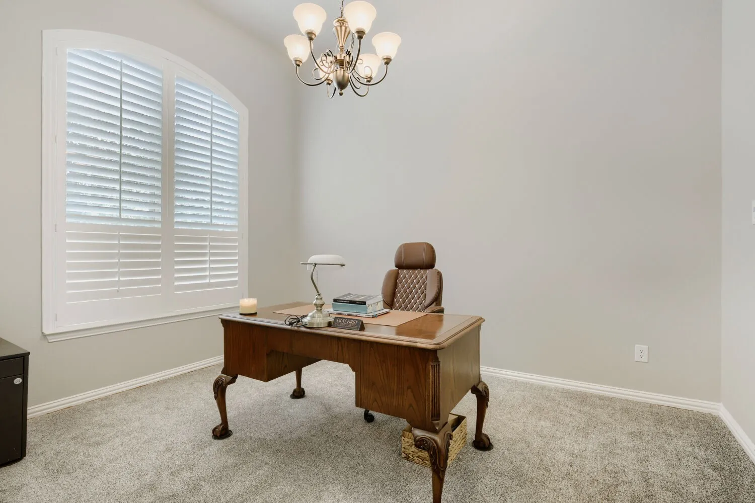 Room featuring an arched window with plantation shutters, light gray wall paint, and gray carpet flooring