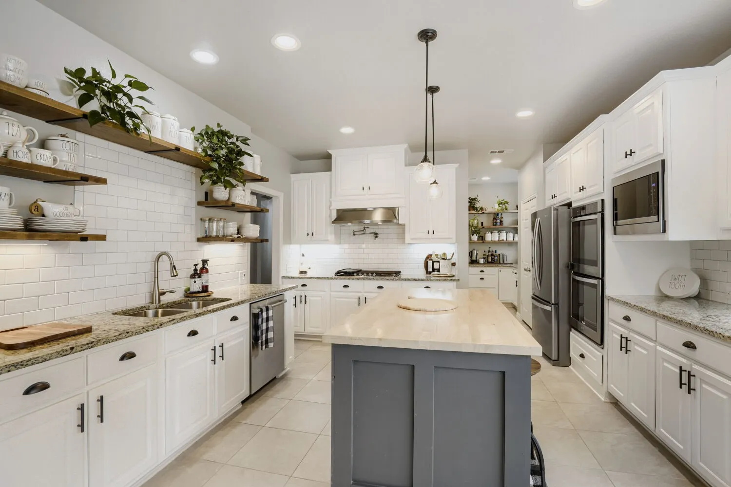Spacious kitchen featuring white cabinetry, granite countertops, and a subway tile backsplash