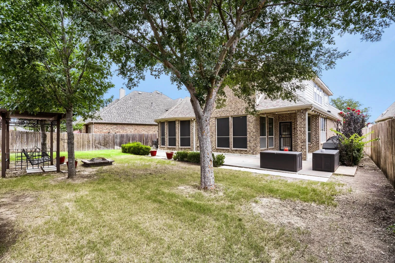 Expansive backyard featuring a mature tree, a paved patio area, and a wood privacy fence