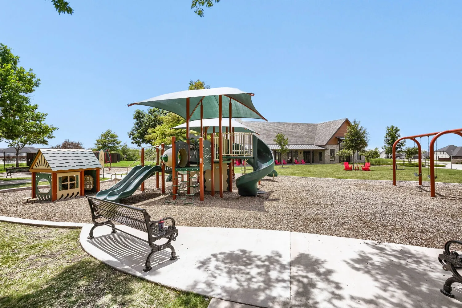 Community playground featuring multiple slides, swings, a playhouse, and a shaded play structure