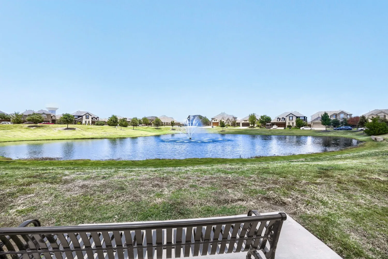 Scenic community pond with a central fountain feature, surrounded by green landscaping
